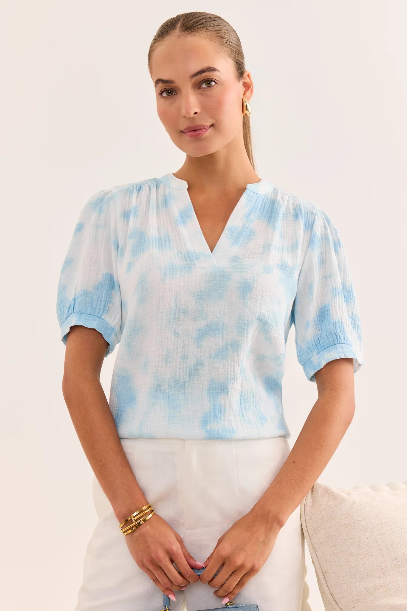 Woman wearing a light blue tie-dye blouse against a white background lifestyle