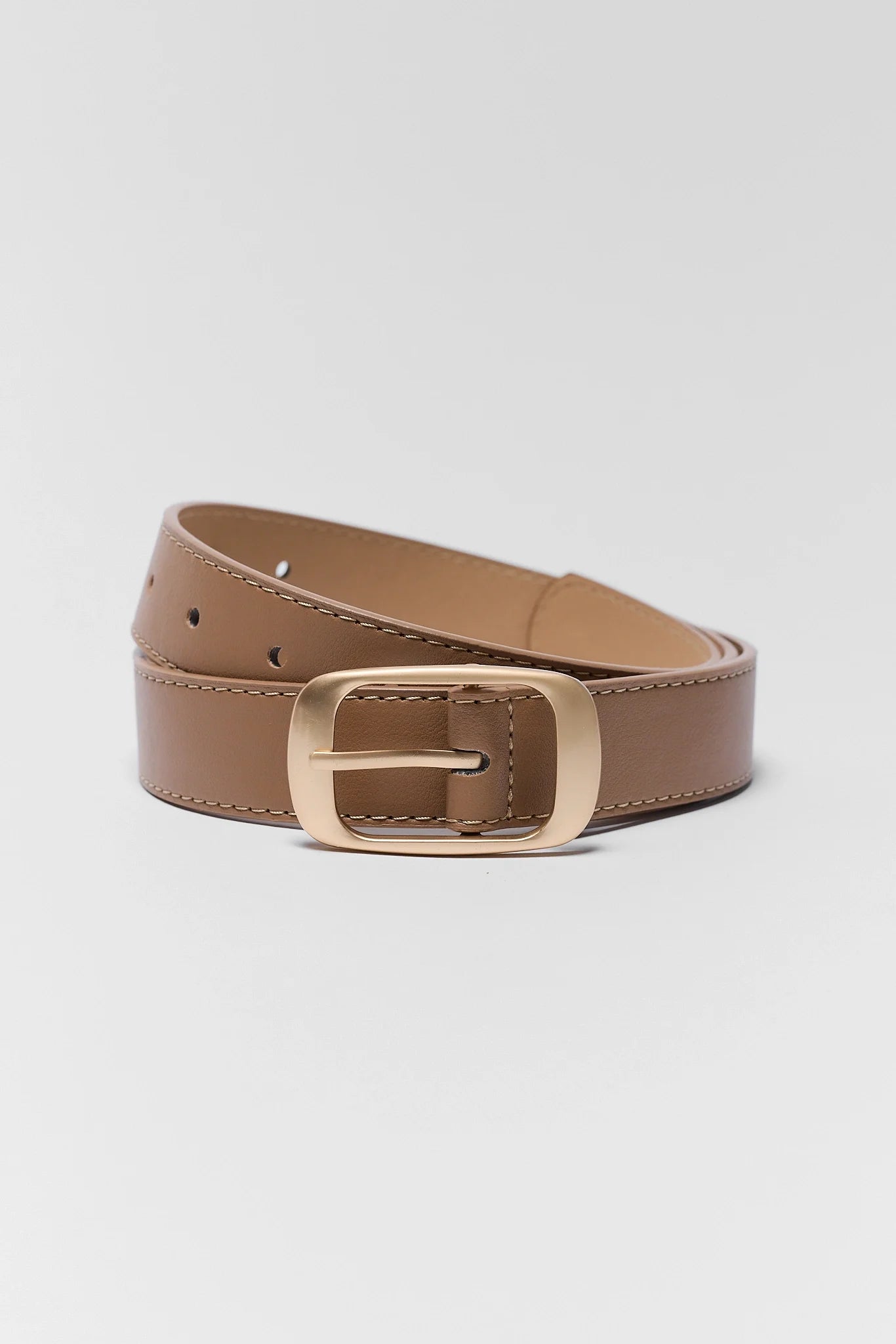 A tan leather belt with a gold-tone metal buckle, neatly coiled on a light gray background.