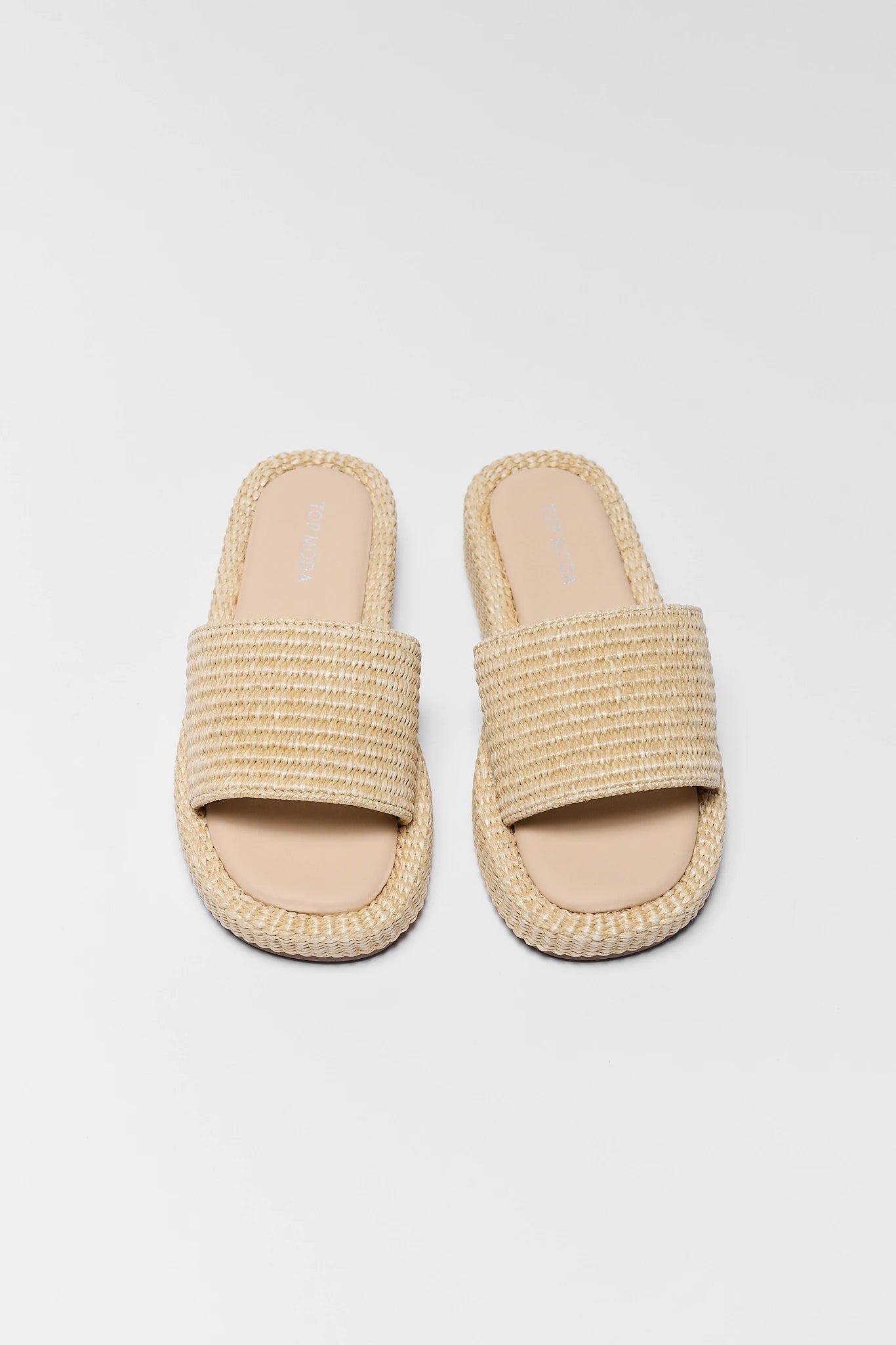 Pair of beige woven sandals on a gray background