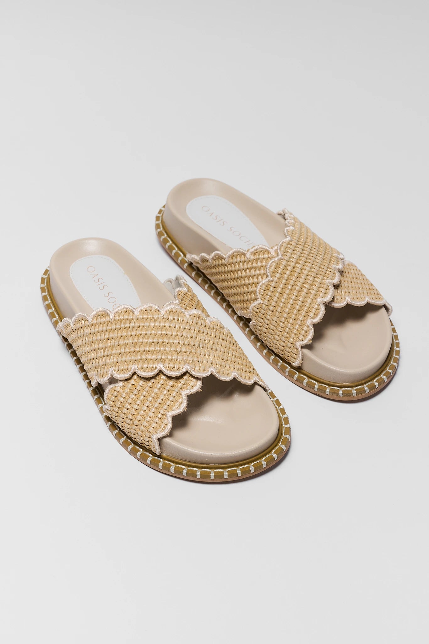 Pair of beige sandals with scalloped edges on a light gray background two