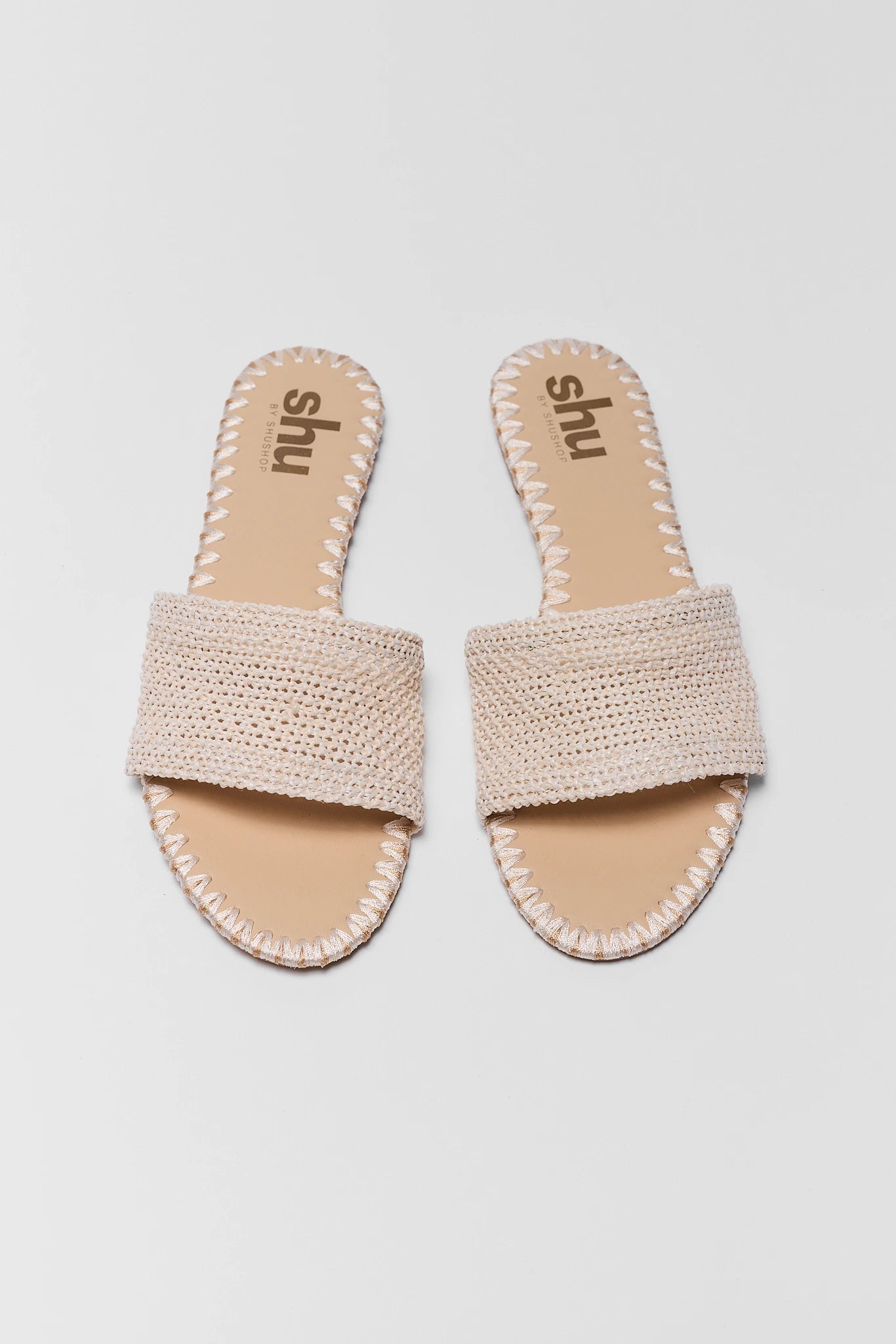 Pair of beige sandals with woven straps on a light gray background two