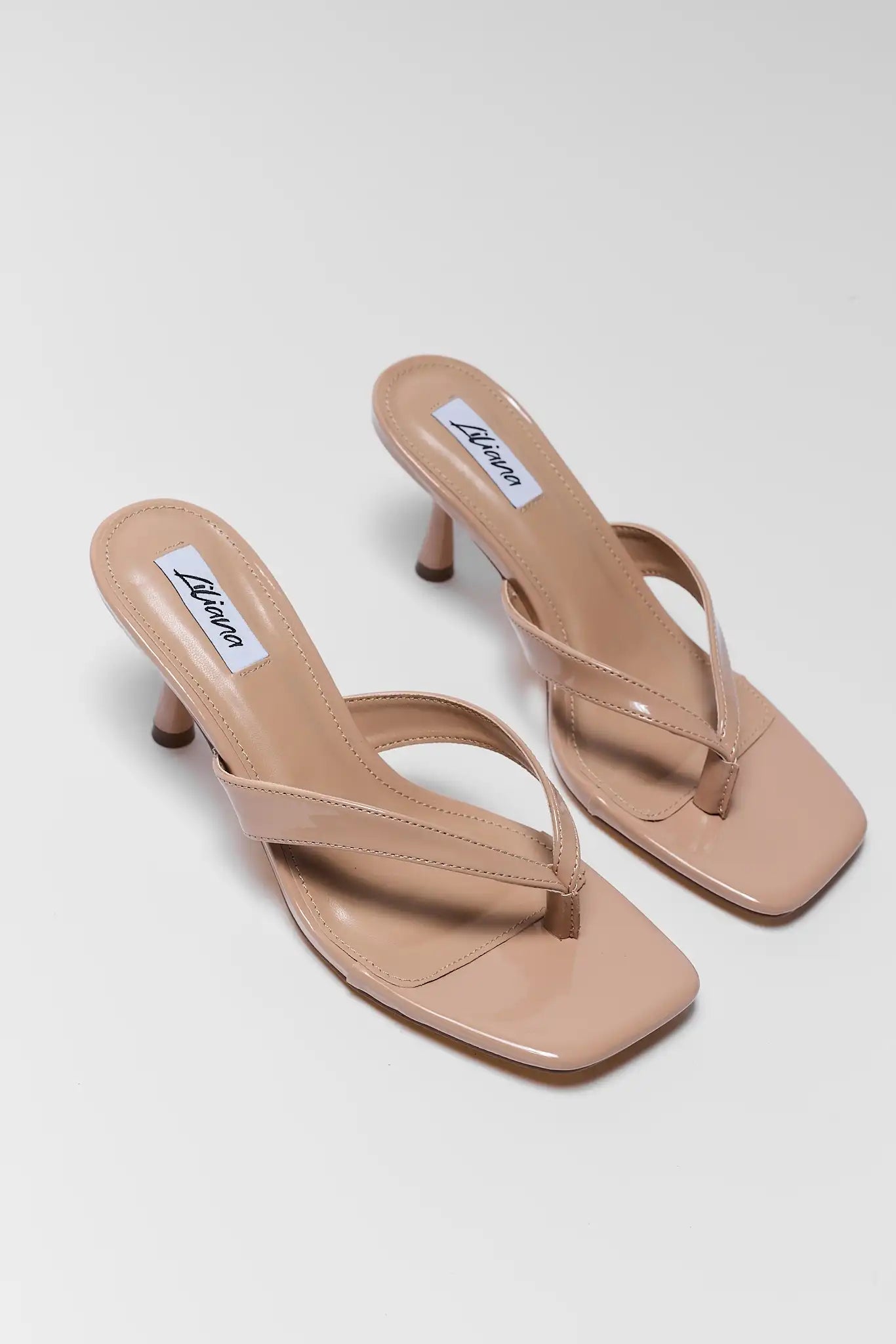 Pair of two beige high-heeled sandals on a light gray background
