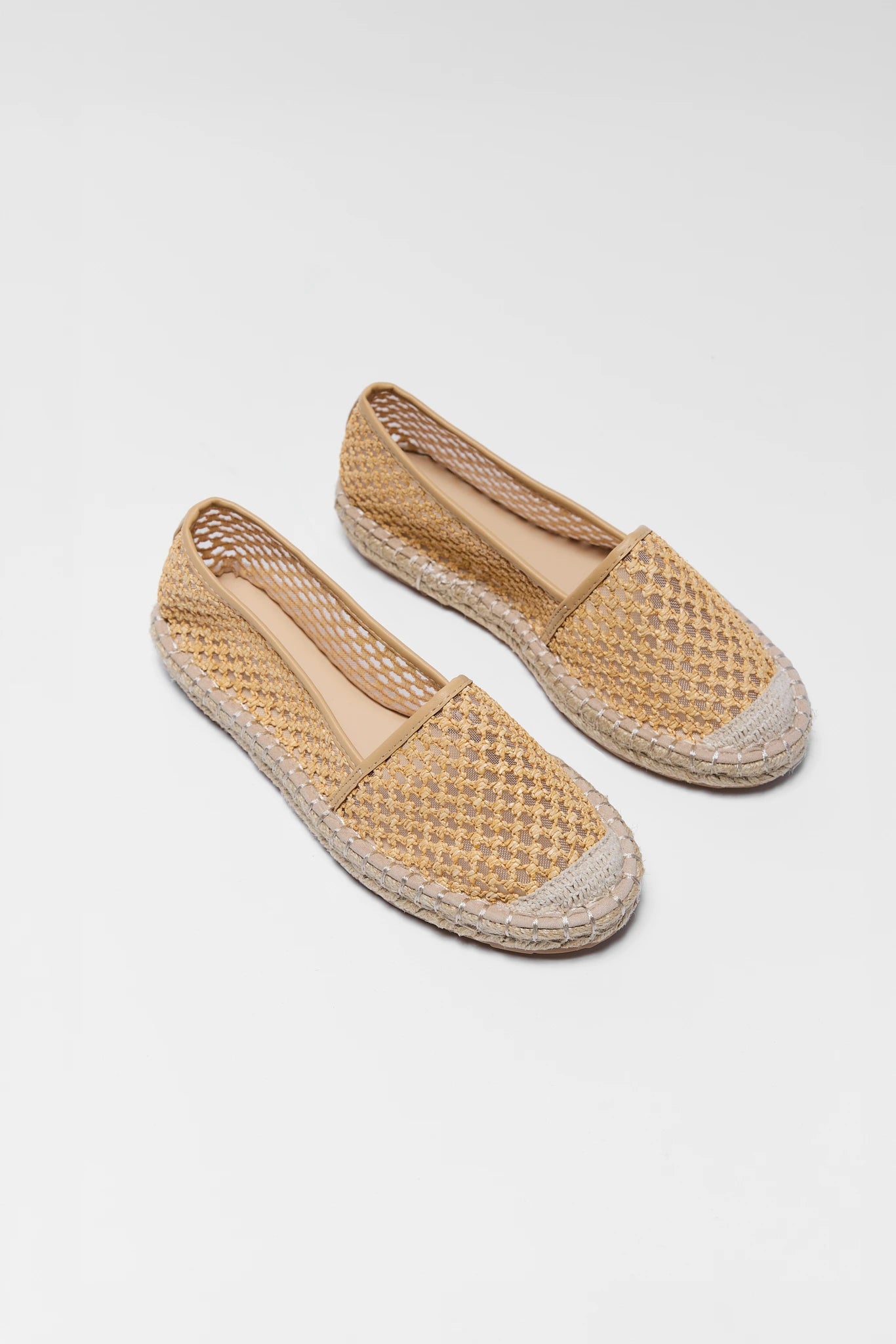 Pair of woven espadrille shoes on a white background two