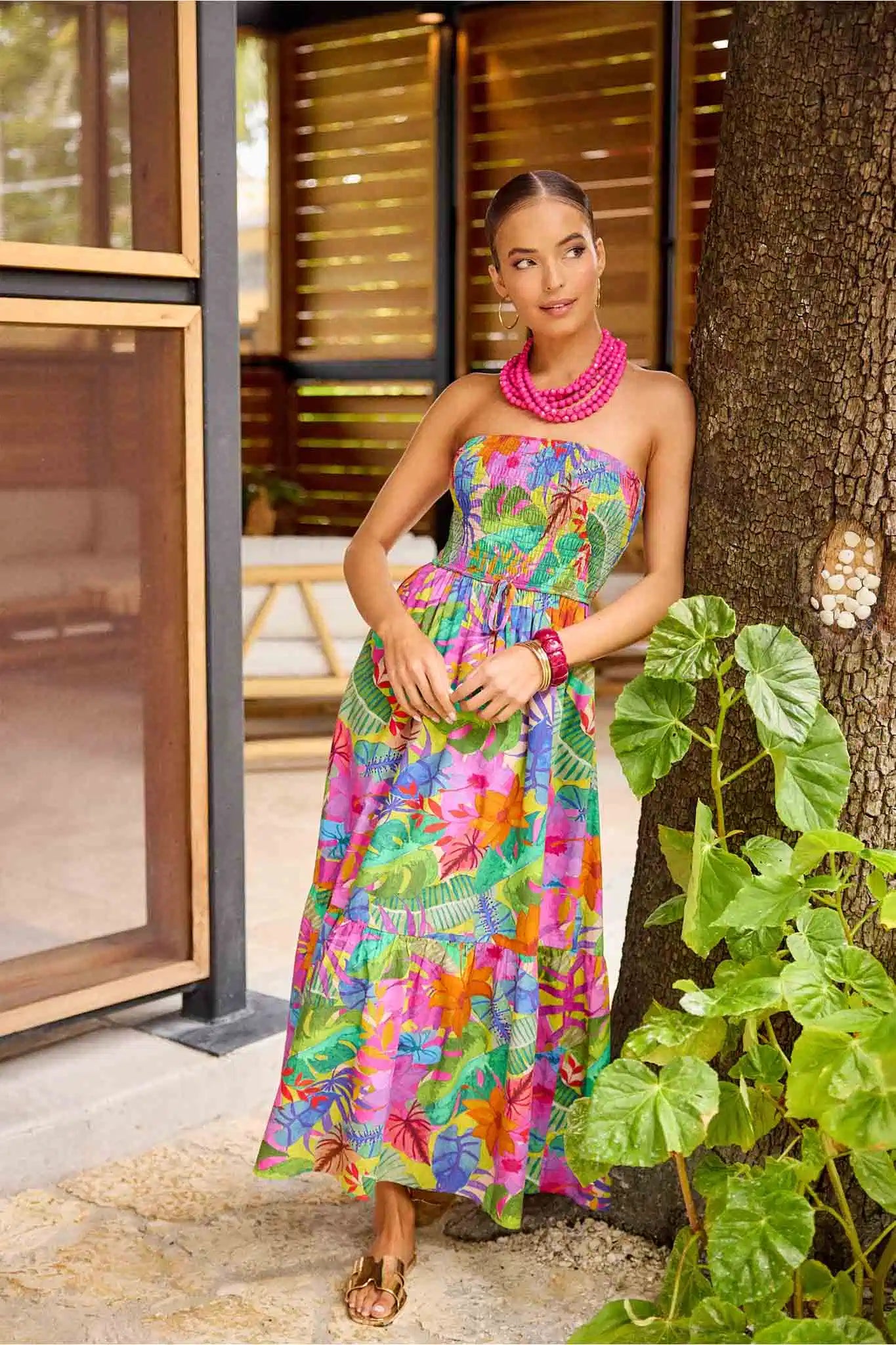 Woman in a colorful dress standing next to a tree outdoors