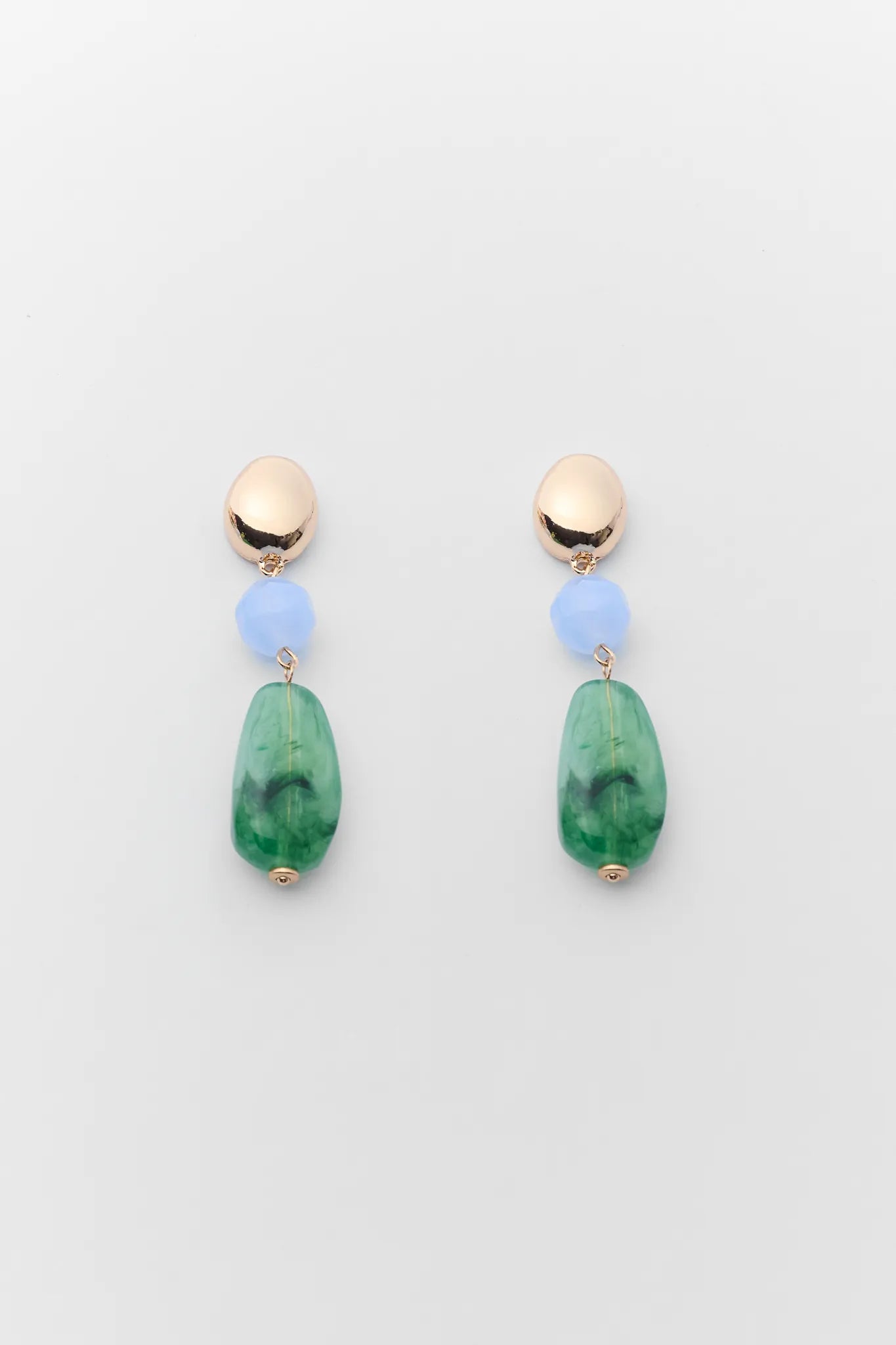 Pair of earrings with green beads and gold tops on a light gray background