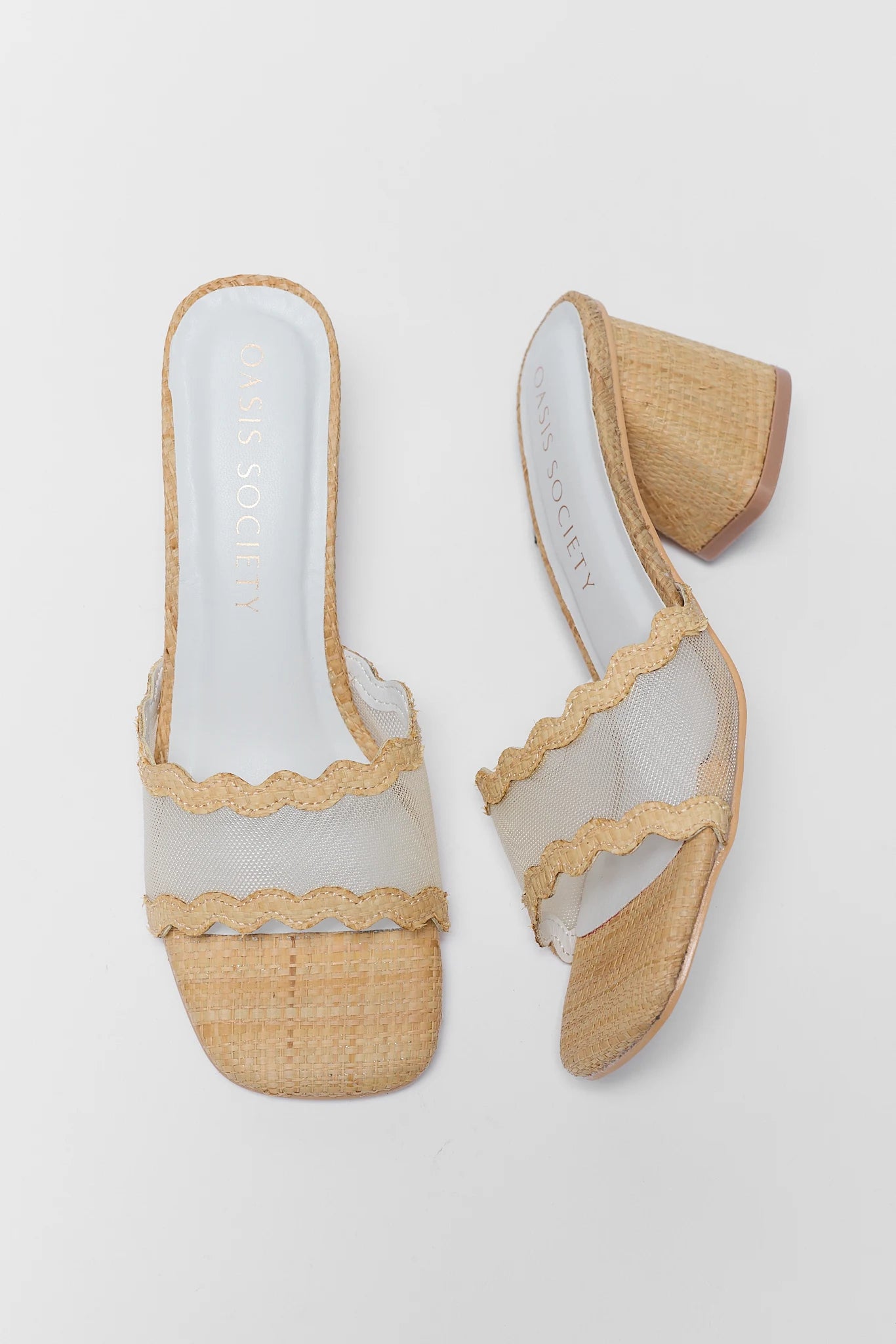 Pair of open-toe shoes with raffia sole and beige trim on a light gray background