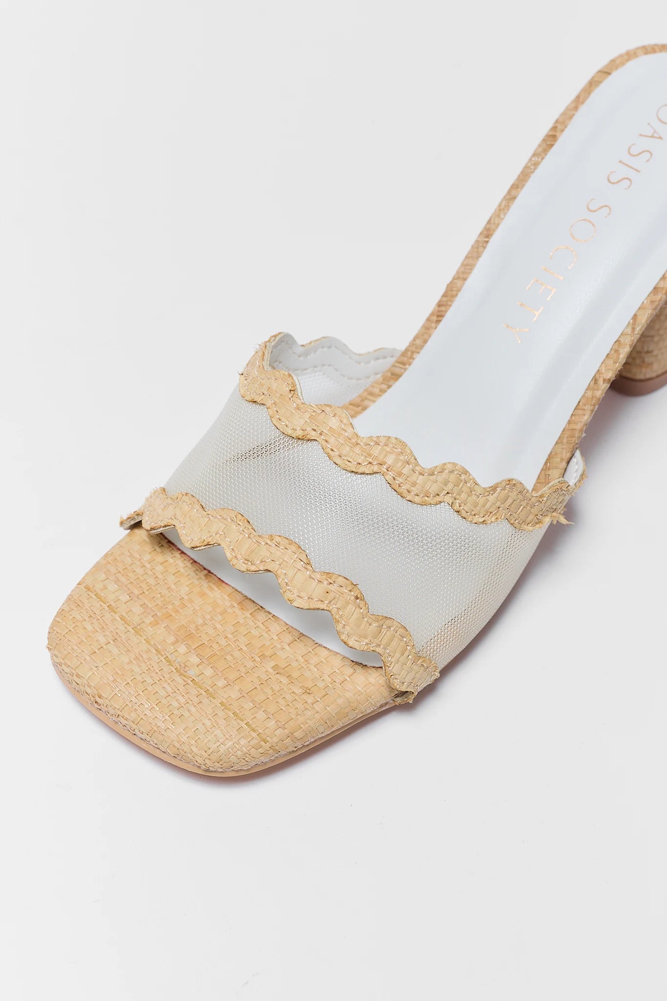 close up White sandal with beige ruffled details on a light gray background