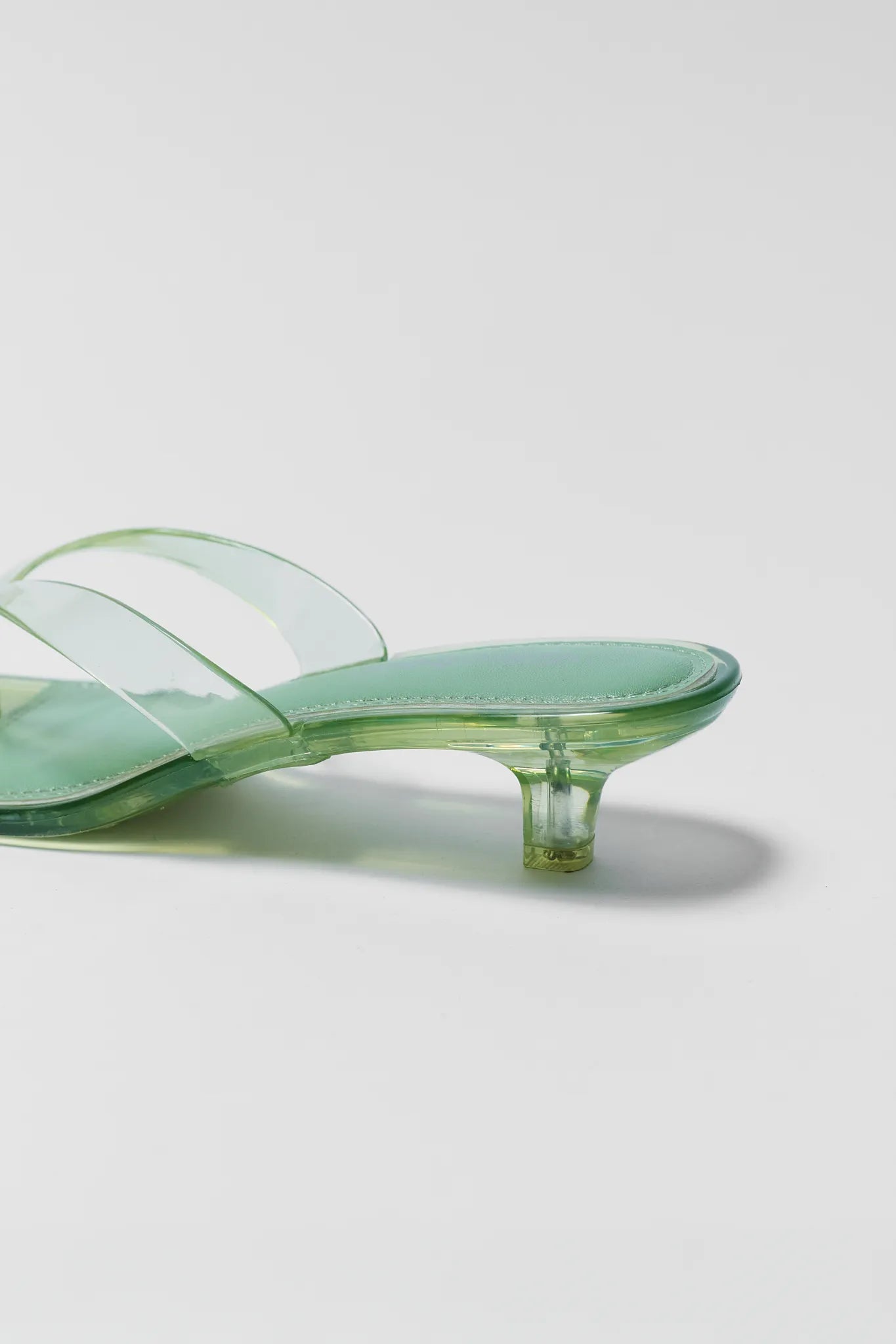 Green transparent sandal with a clear heel on a light gray background