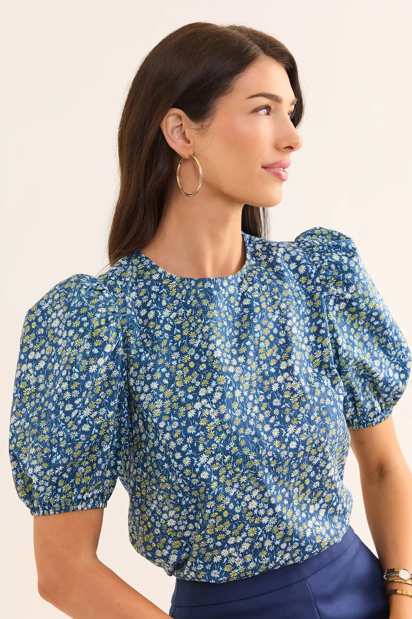 Woman wearing a blue floral blouse with puffed sleeves on a beige background lifestyle
