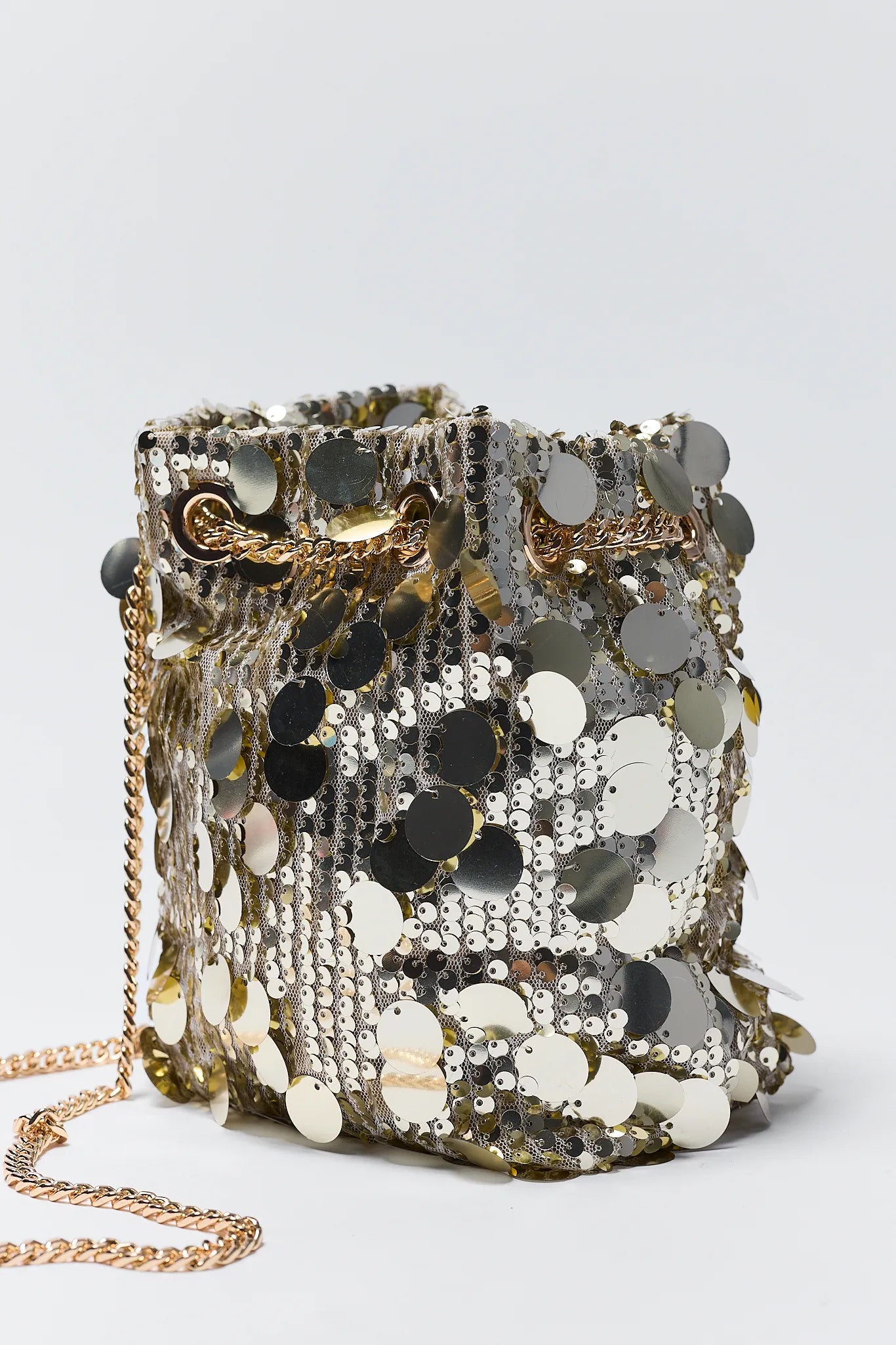 Sparkling sequin handbag with a gold chain on a light gray background