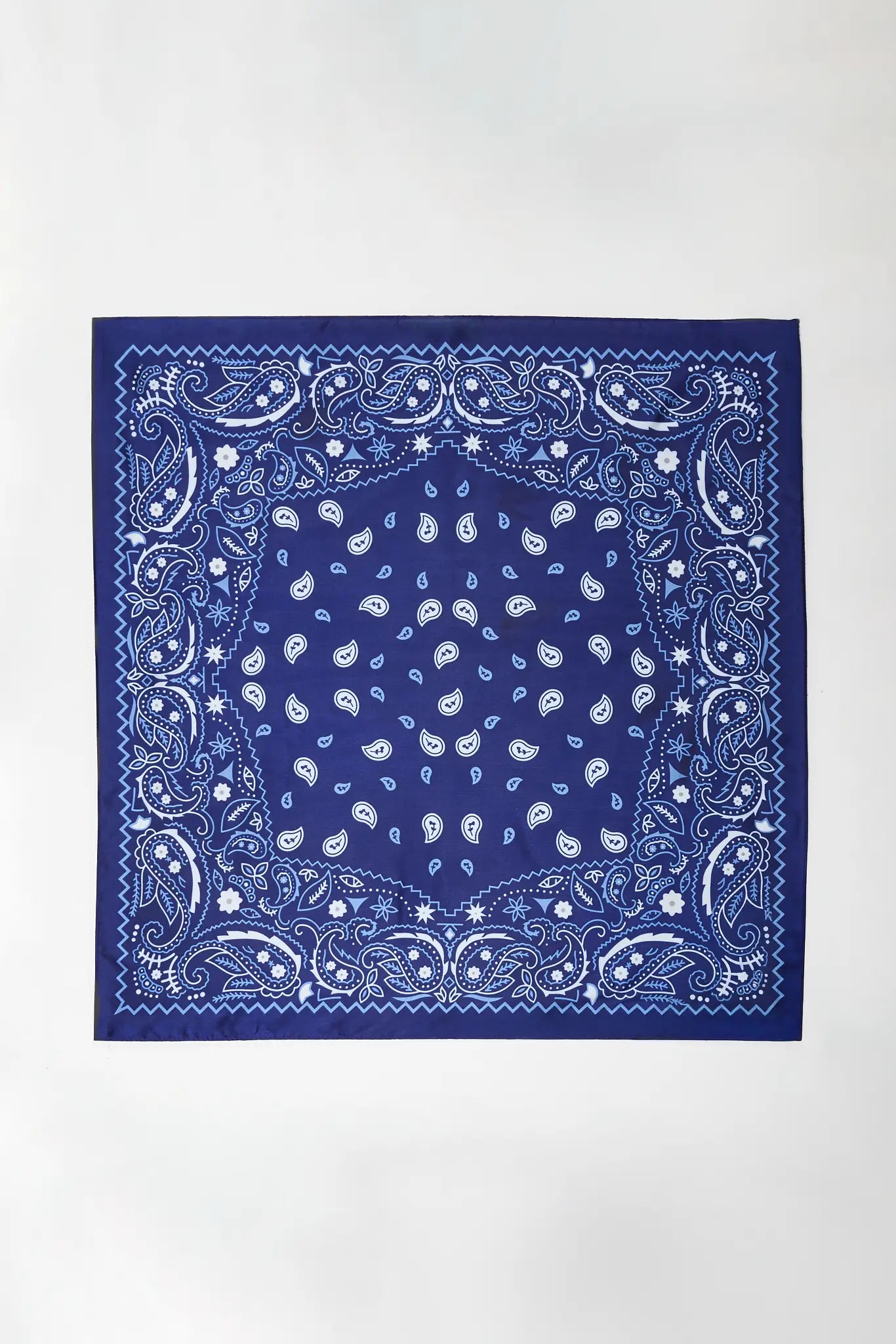 A square bandana with a classic paisley pattern in royal blue and white, laid flat against a clean white background.