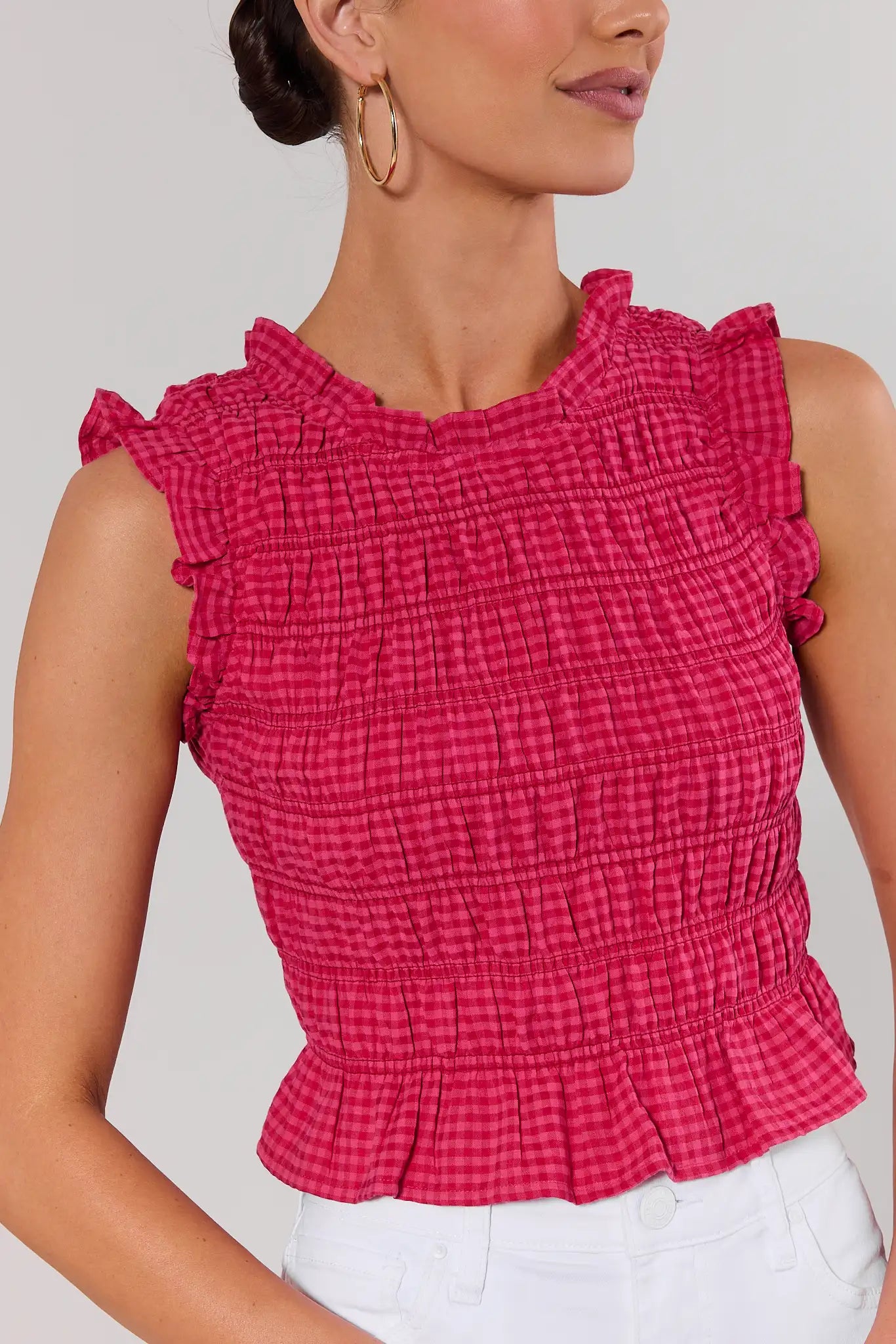 close up Woman wearing a red checkered top with ruffled details on a plain background