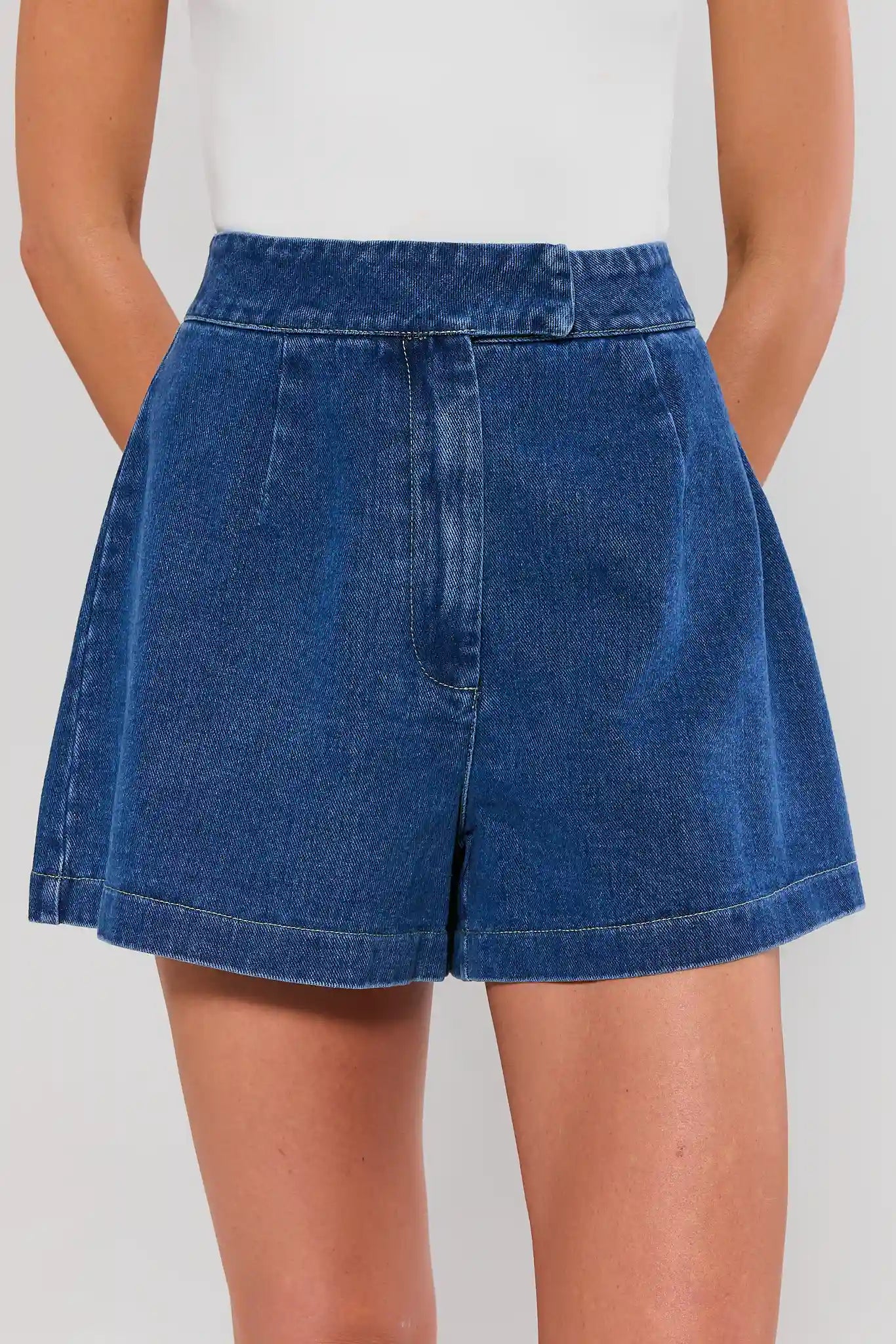 Blue denim shorts worn by a person on a plain background