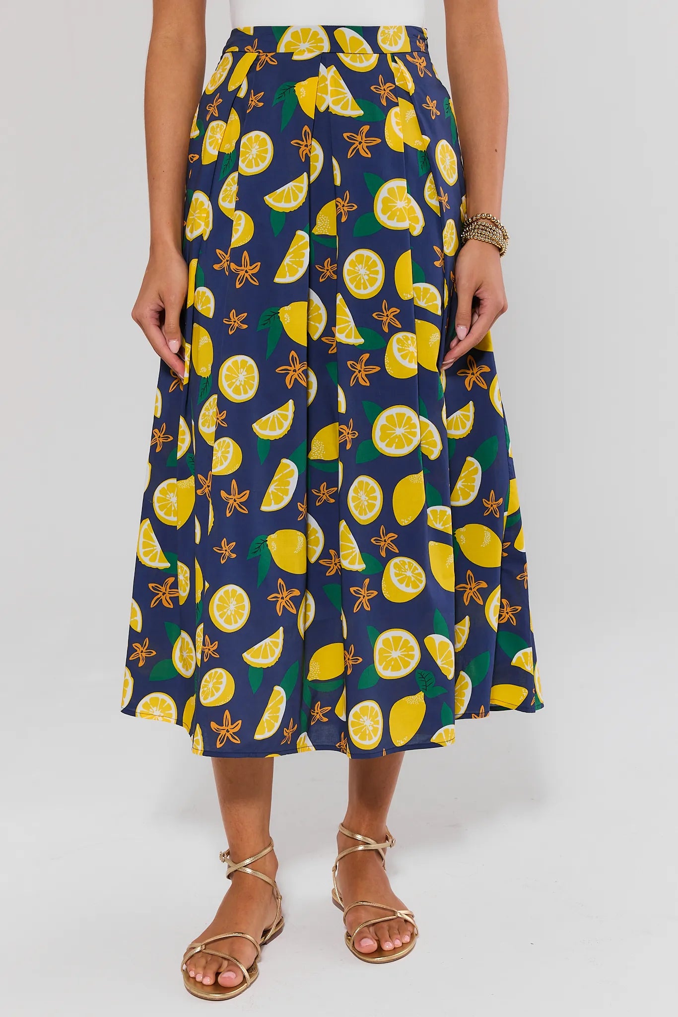 Person wearing a navy blue skirt with lemon pattern on a white background
