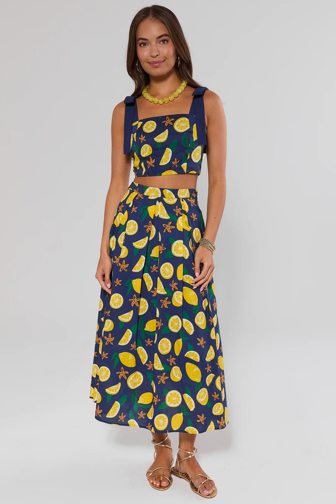 Woman wearing a two-piece outfit with lemon pattern on a plain background