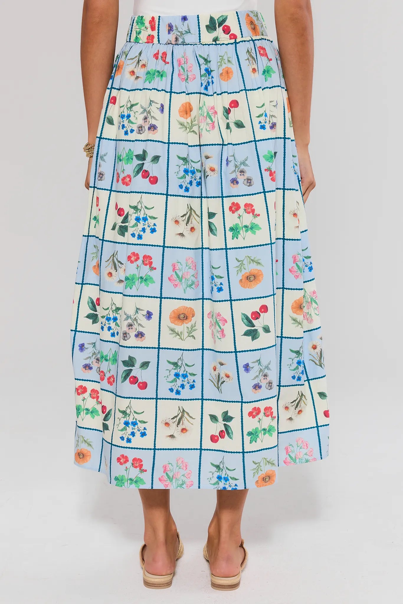 Person standing wearing a floral checkered skirt on a white background