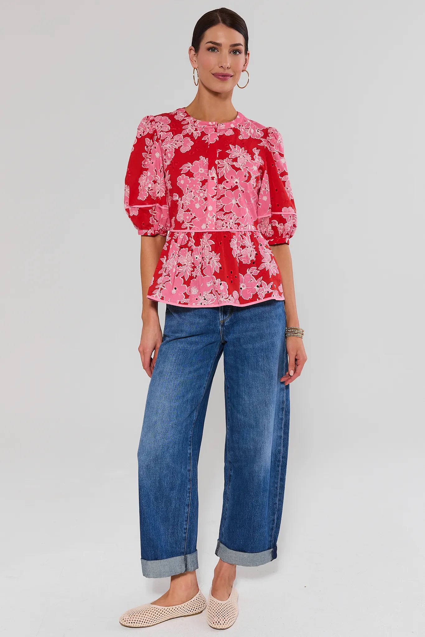 Woman wearing a red floral blouse and blue jeans on a white background