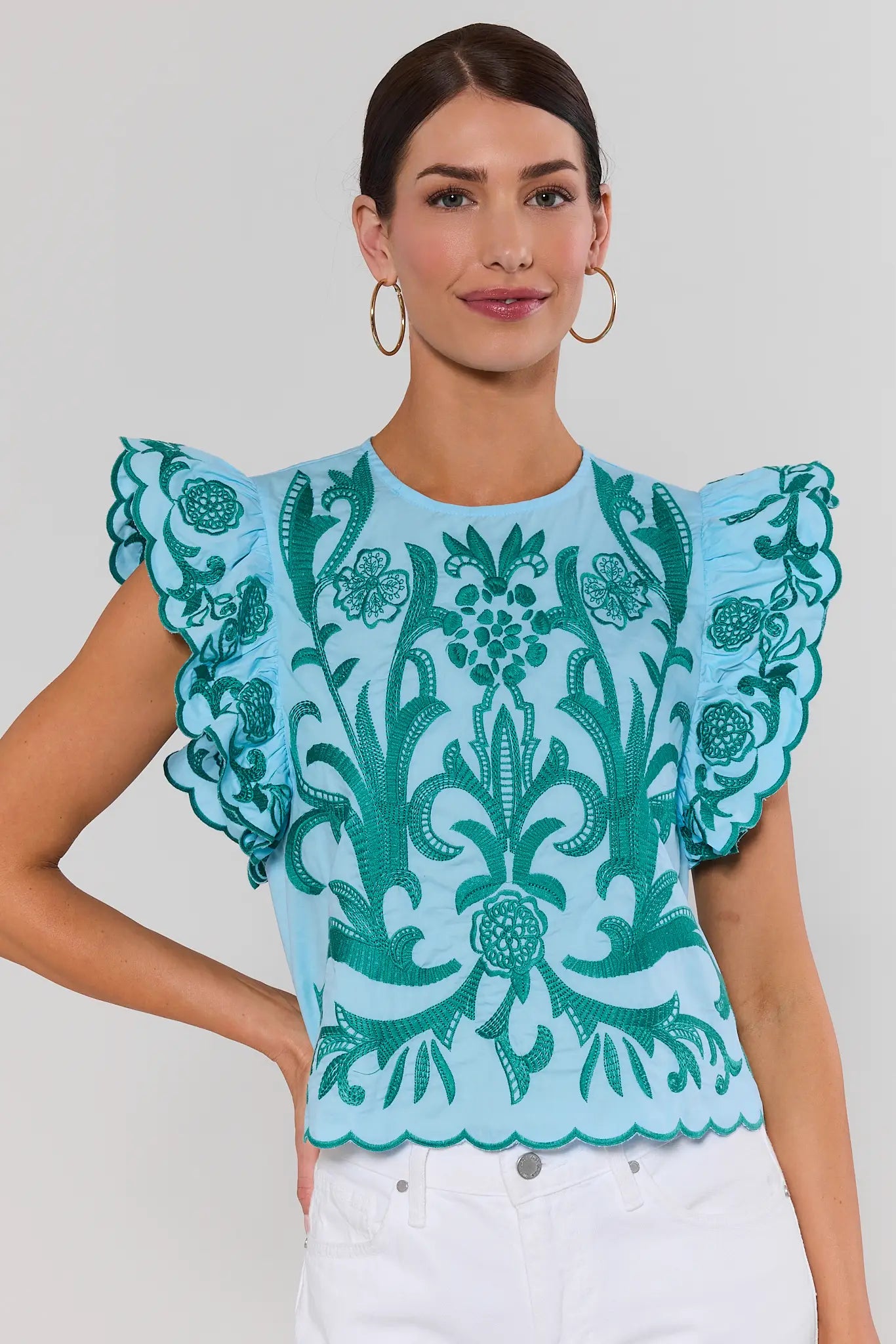 Woman wearing a blue top with green floral patterns on a plain background