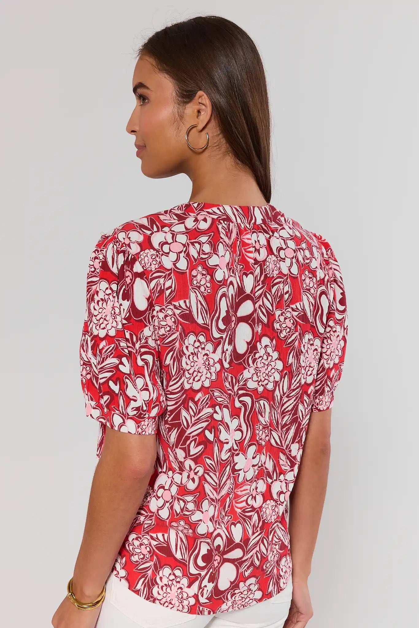 Woman wearing a red floral blouse against a white background standing