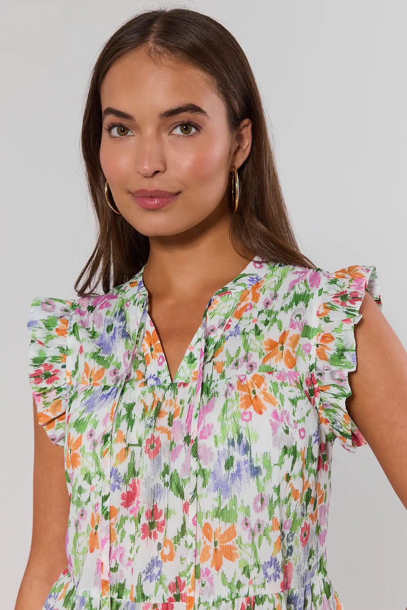 close up Woman wearing a colorful floral faye top against a plain background