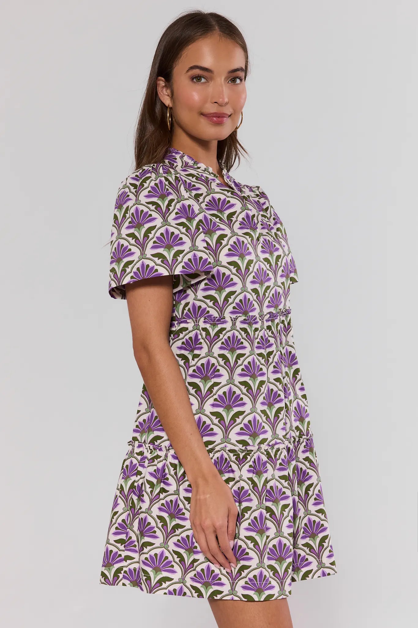 side shot Woman wearing a patterned dress on a plain background