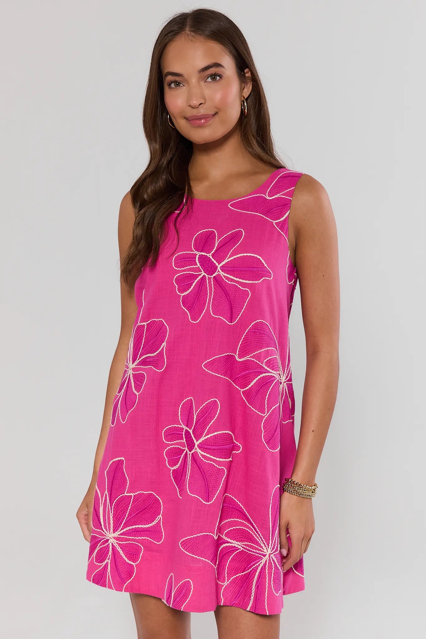 Woman wearing a pink dress with floral patterns on a plain background