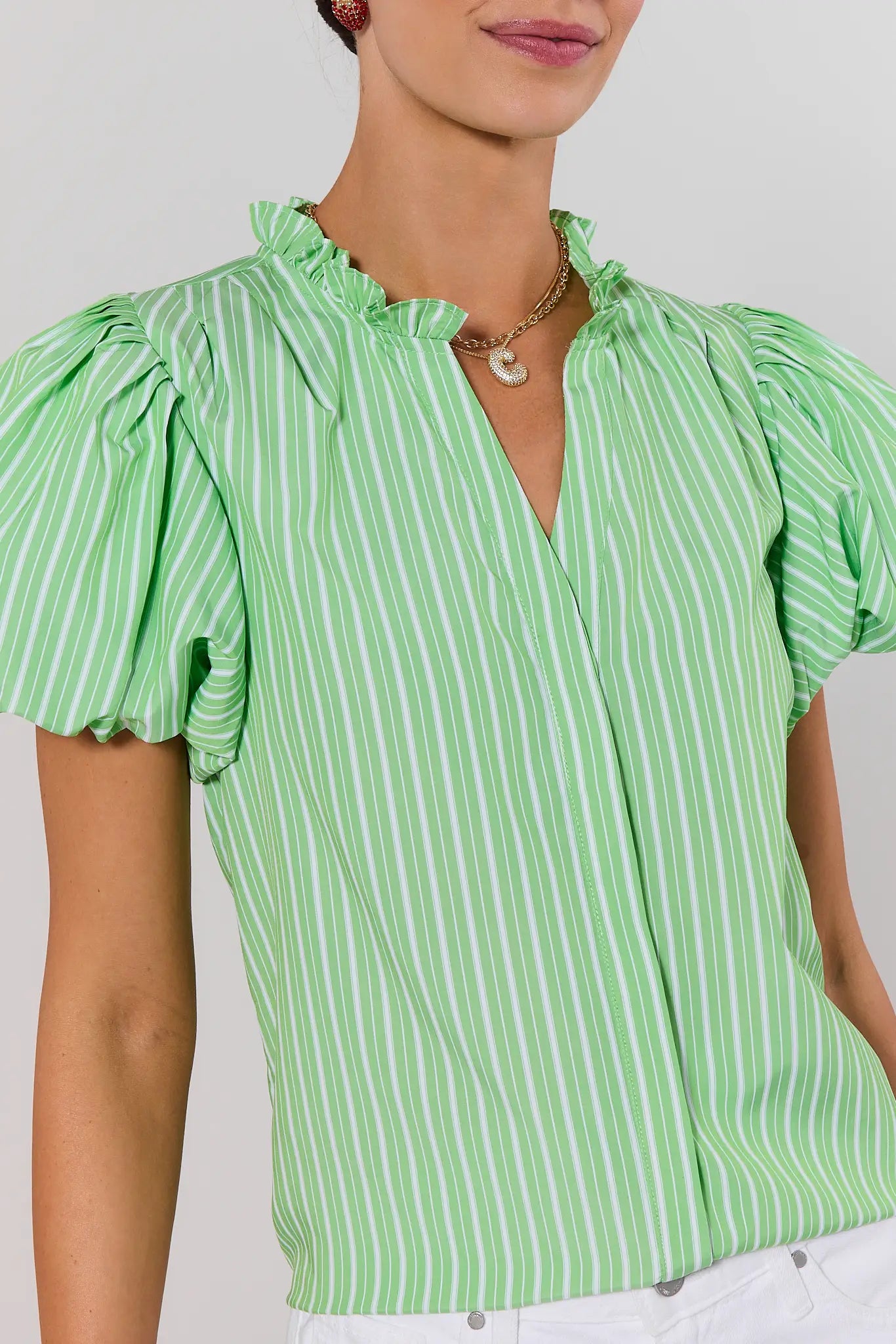close up Green and white striped blouse with ruffled collar on a plain background