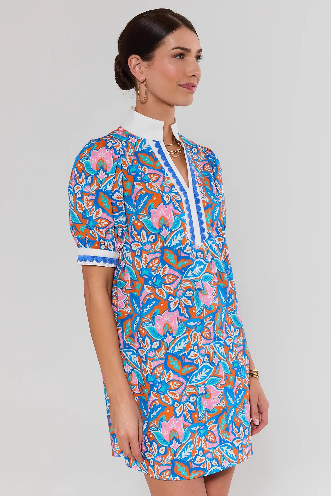 side shot Woman wearing a colorful floral dress on a white background