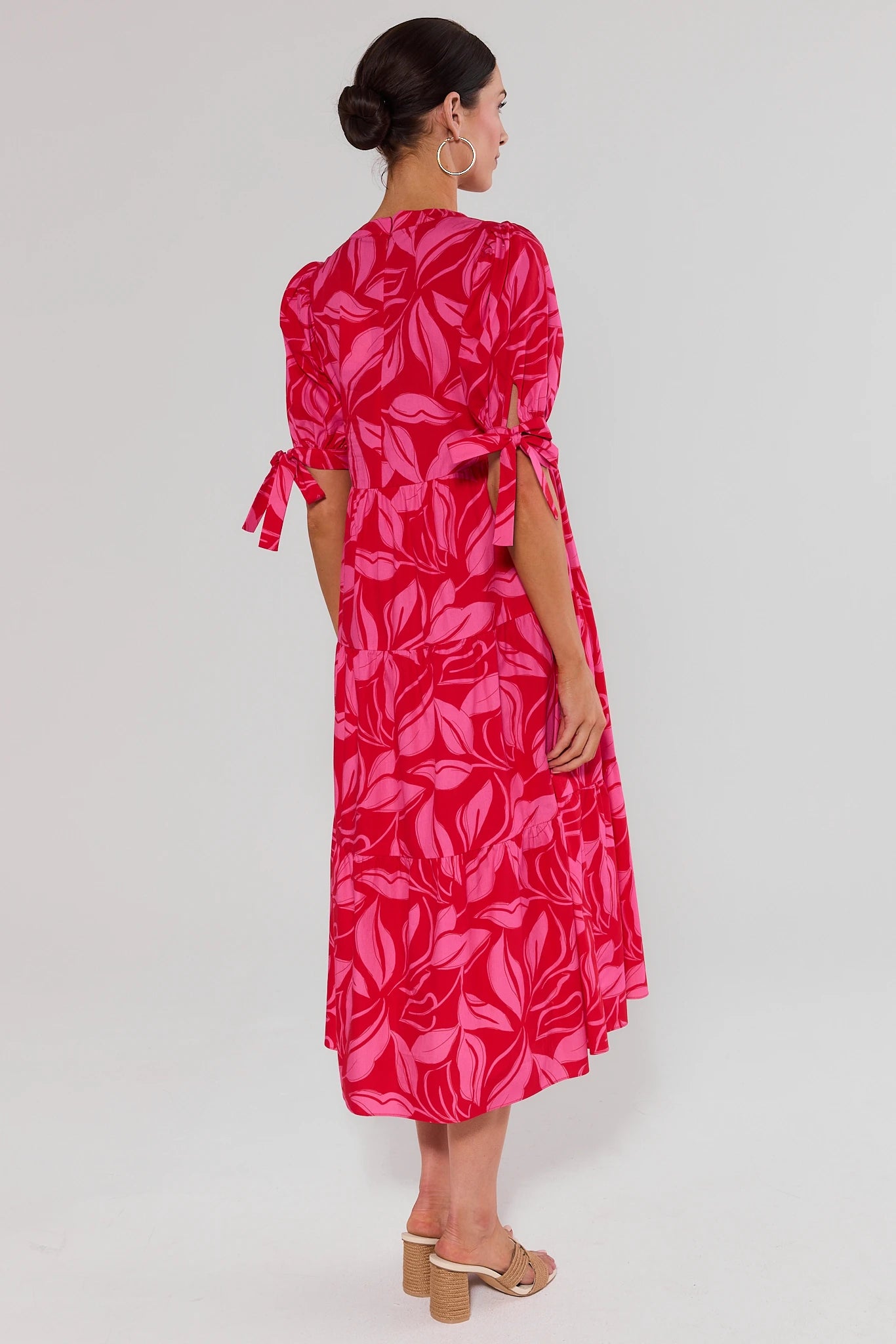 Woman standing wearing a red leaf-patterned dress on a white background