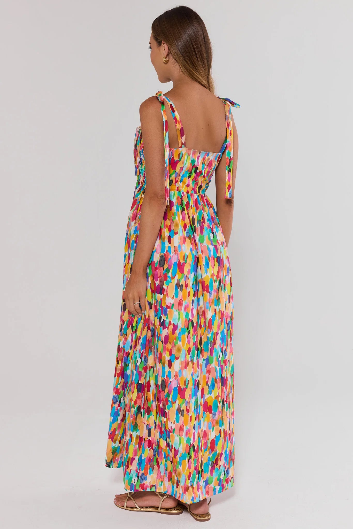 Woman wearing a colorful patterned dress on a white background standing 