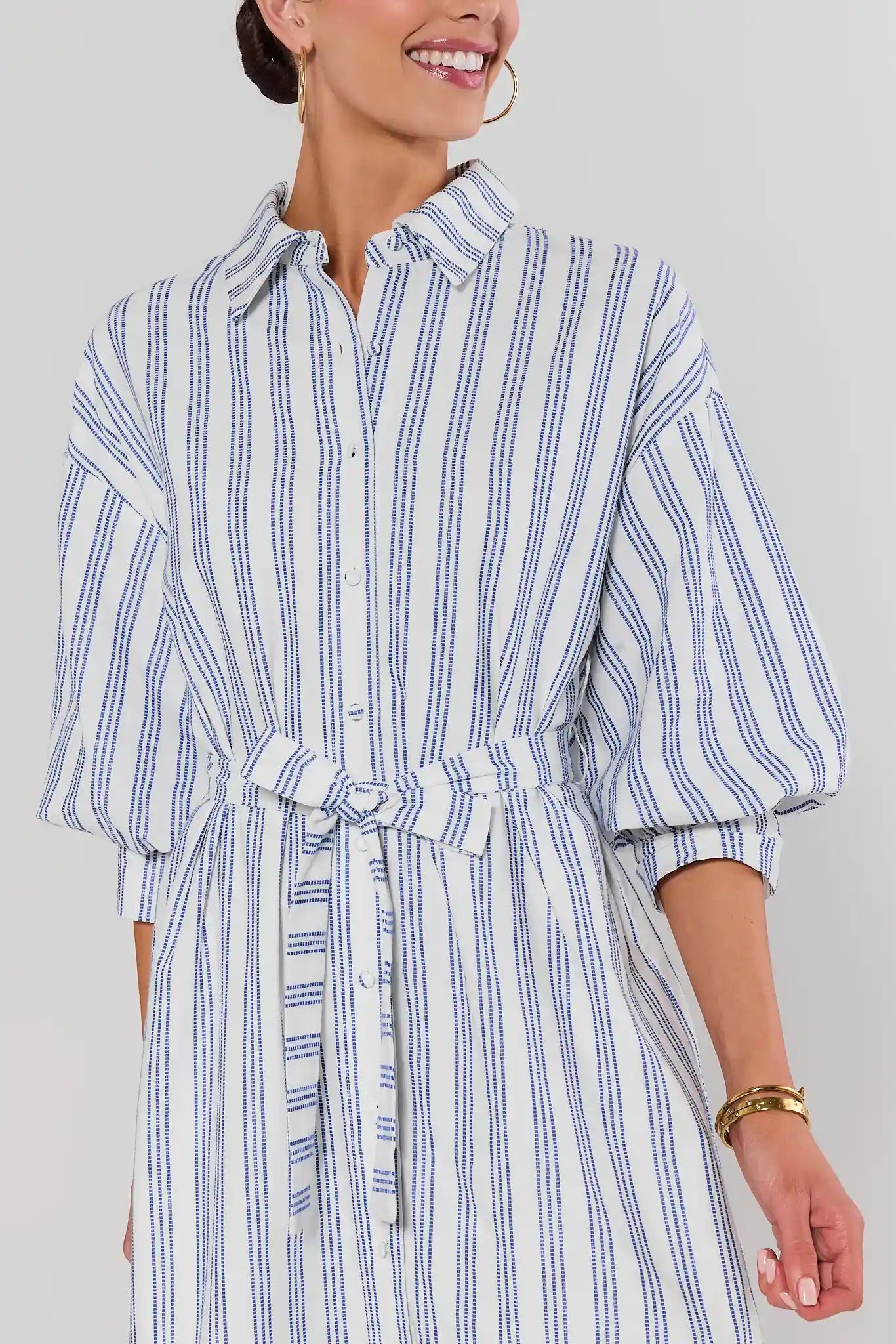 close up Woman wearing a blue and white striped dress against a plain background