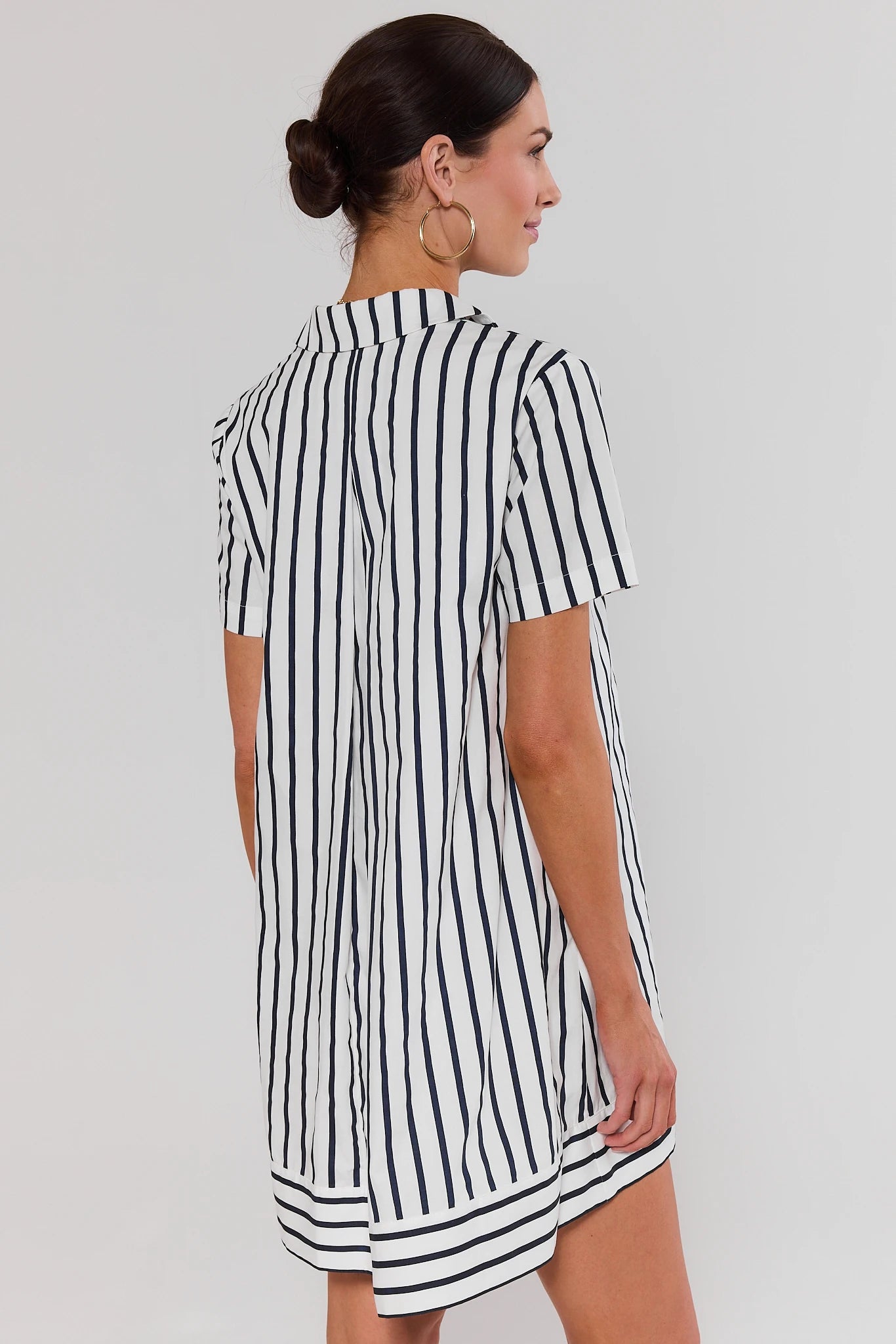 Woman wearing a black and white striped dress on a plain background standing