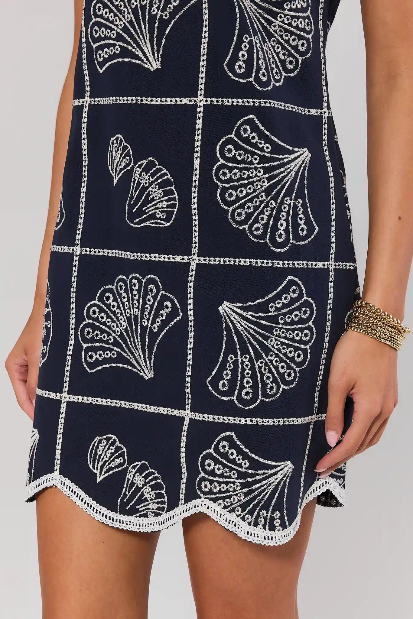 Navy blue dress with white shell pattern worn by a person on a plain background close up 