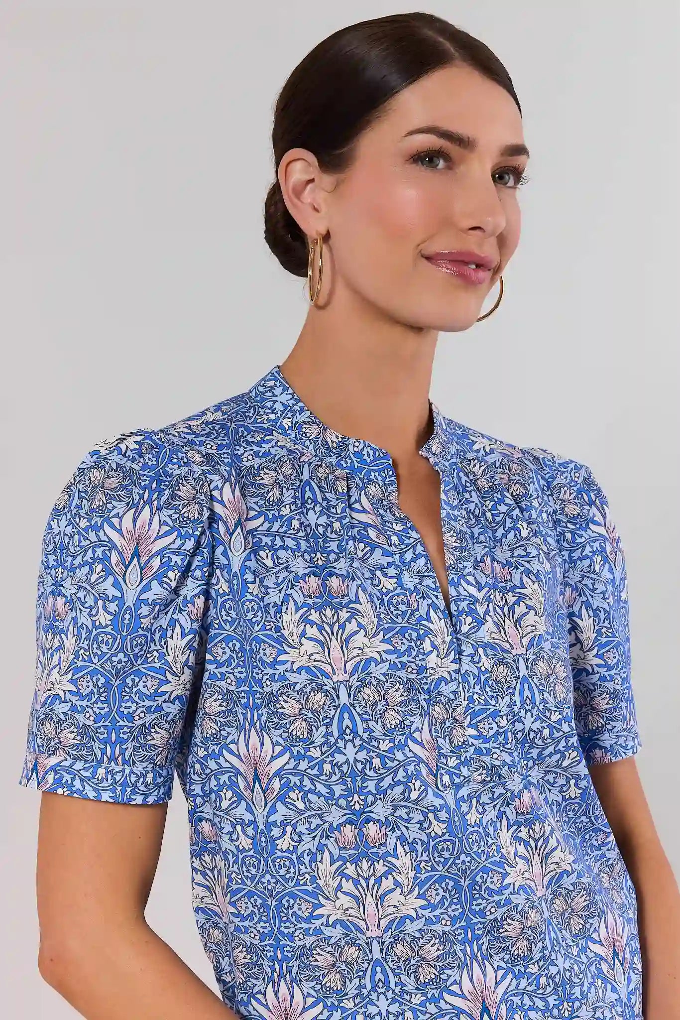 close up Woman wearing a blue floral patterned top against a plain background