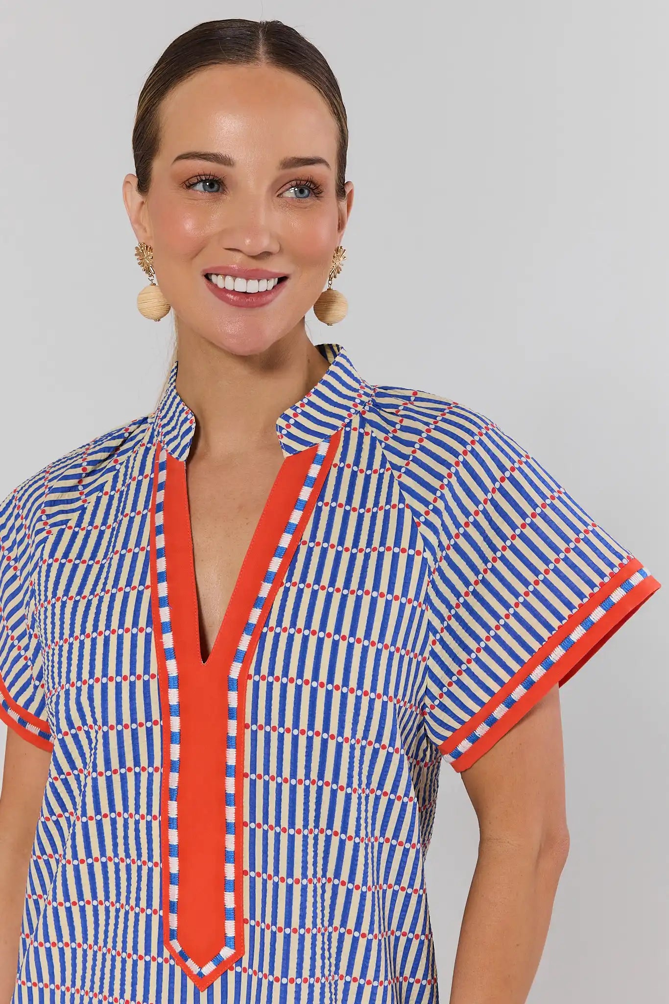 close up Woman wearing a blue and orange patterned dress against a gray background