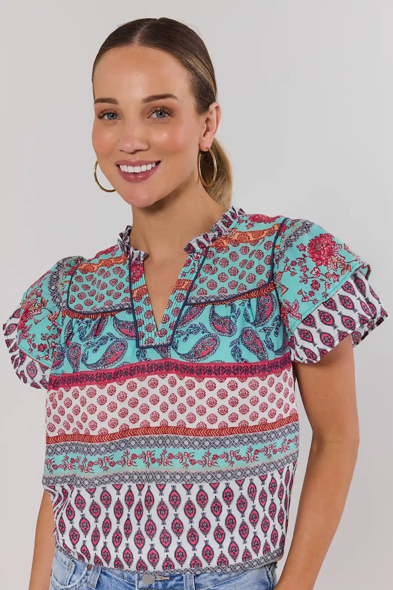 close up Woman wearing a colorful patterned blouse against a plain background