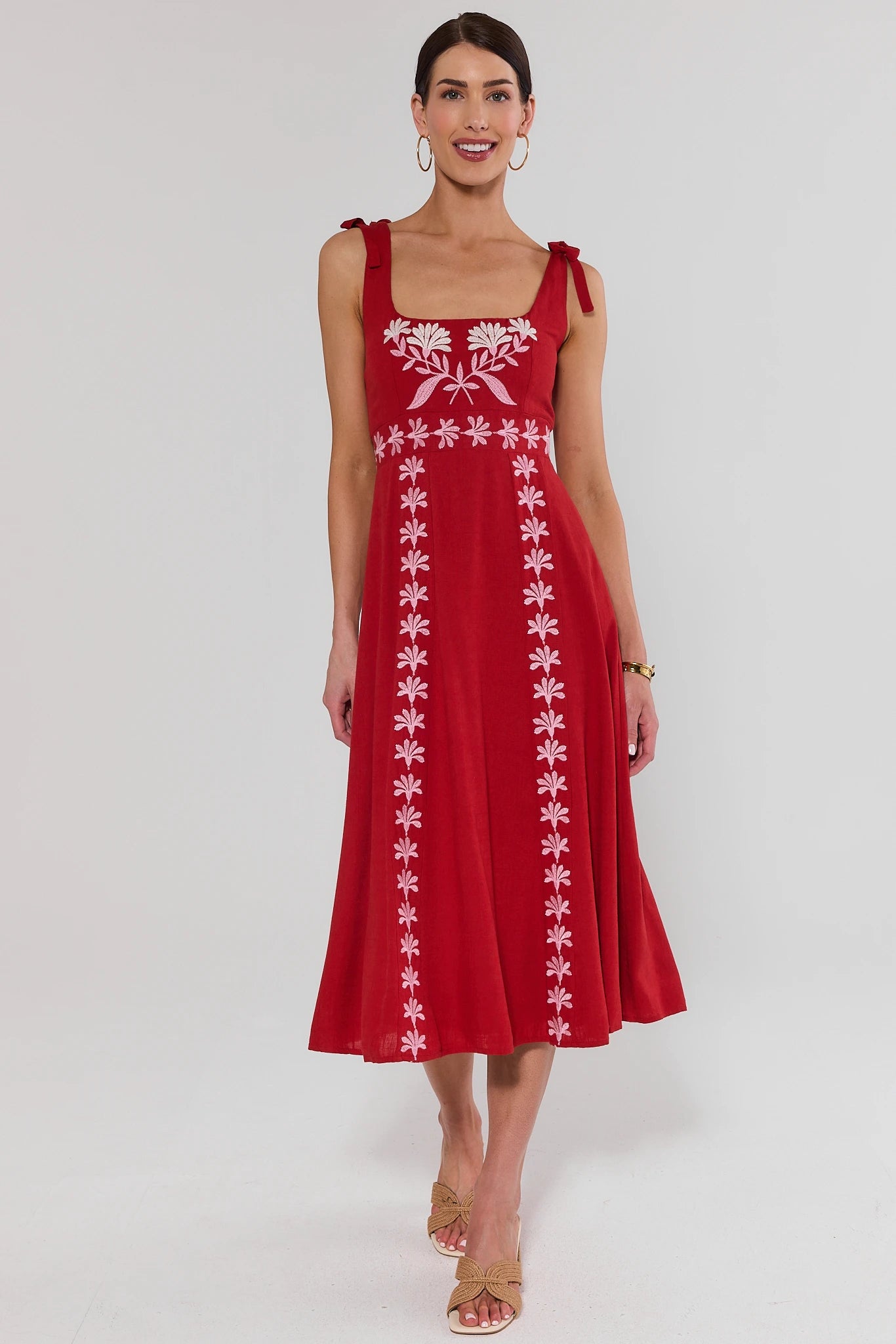 Woman wearing a red dress with white floral patterns on a white background standing