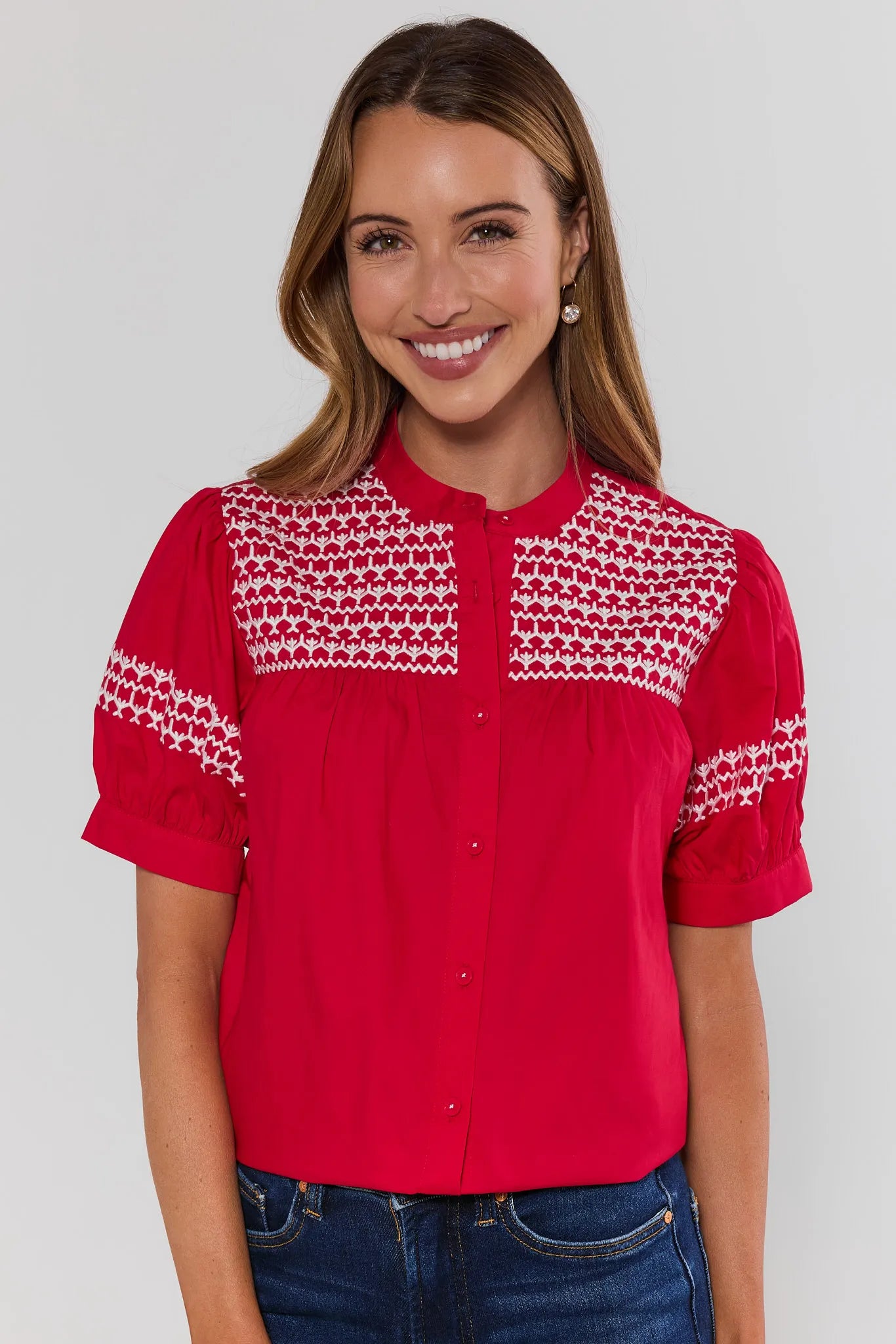 Woman wearing a red blouse with white patterns on a plain background