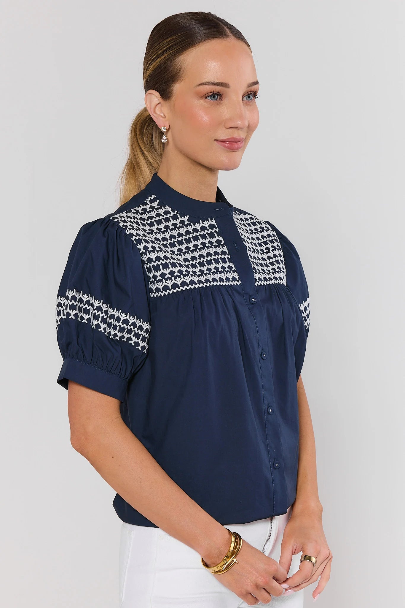 side shot Woman wearing a navy blue blouse with white pattern on a plain background