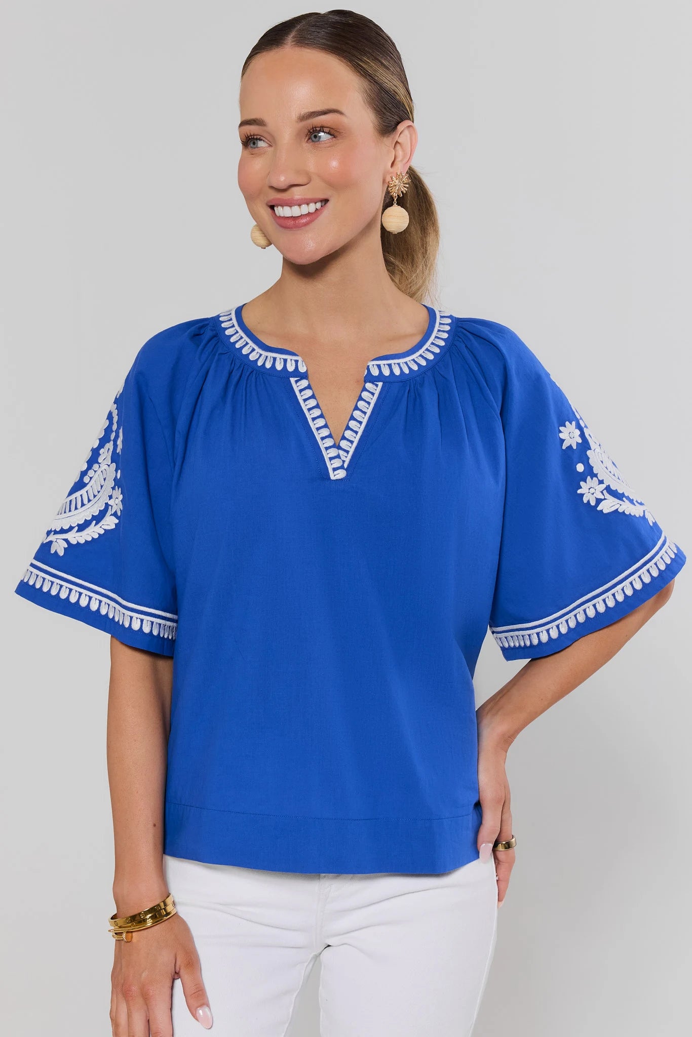 Woman wearing a blue blouse with white embroidery on a background