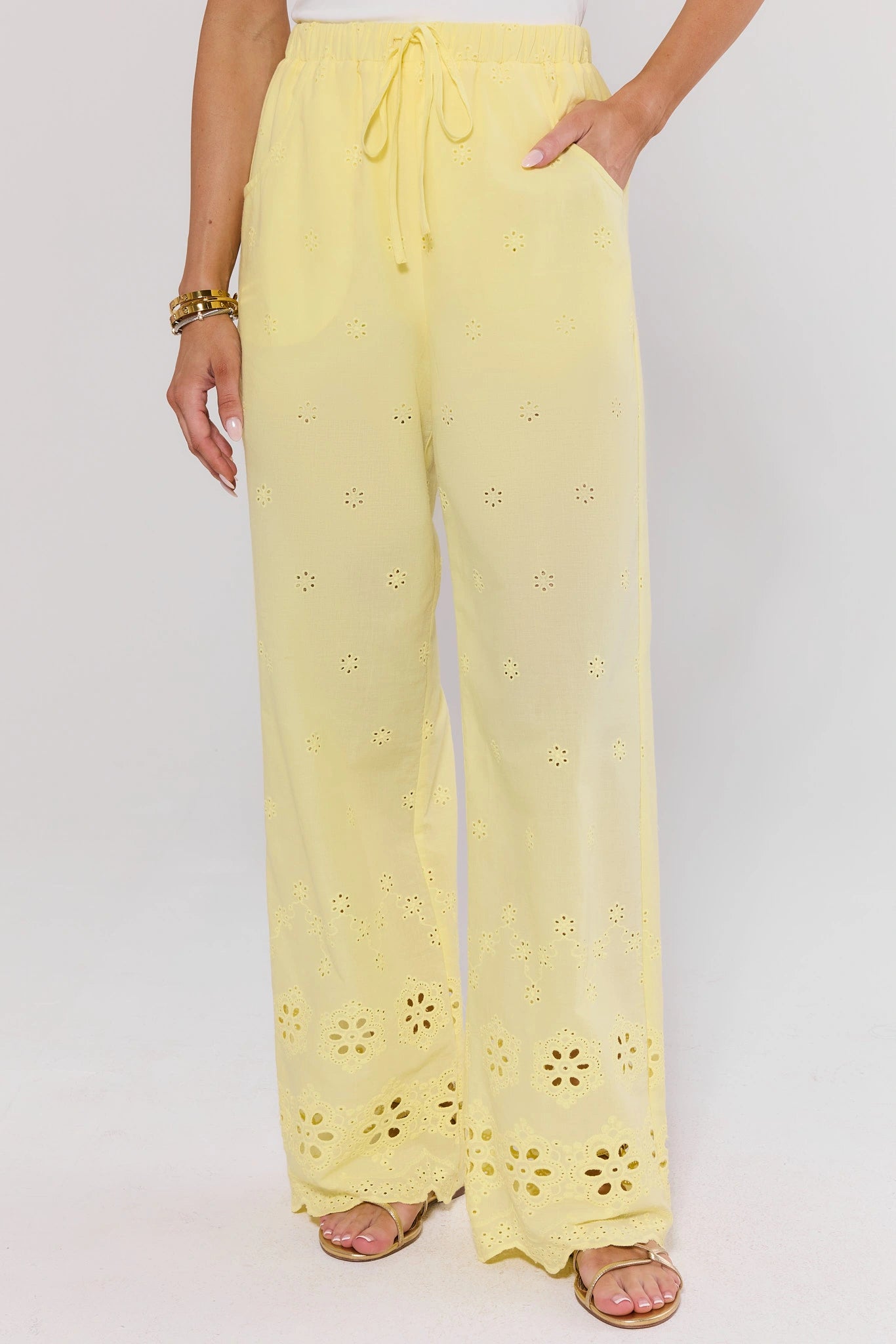 Yellow pants with floral cut-out details on a white background