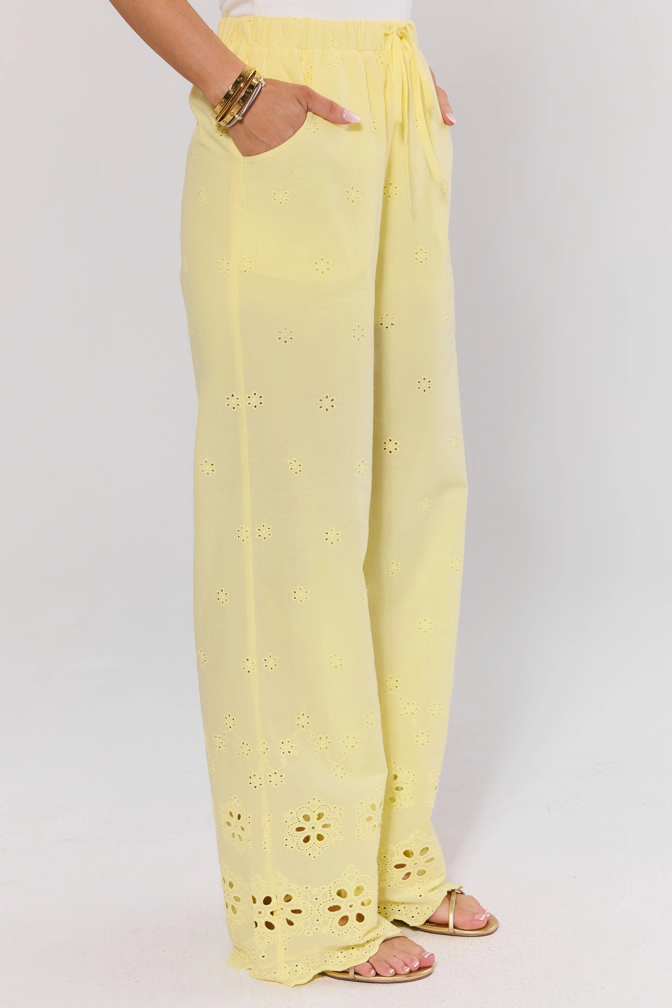 side shot Yellow pants with floral cut-out details worn by a person on a white background