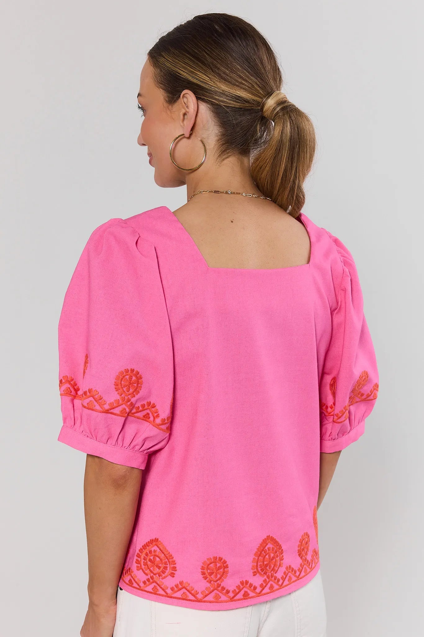 Pink blouse with orange embroidery on a plain background standing