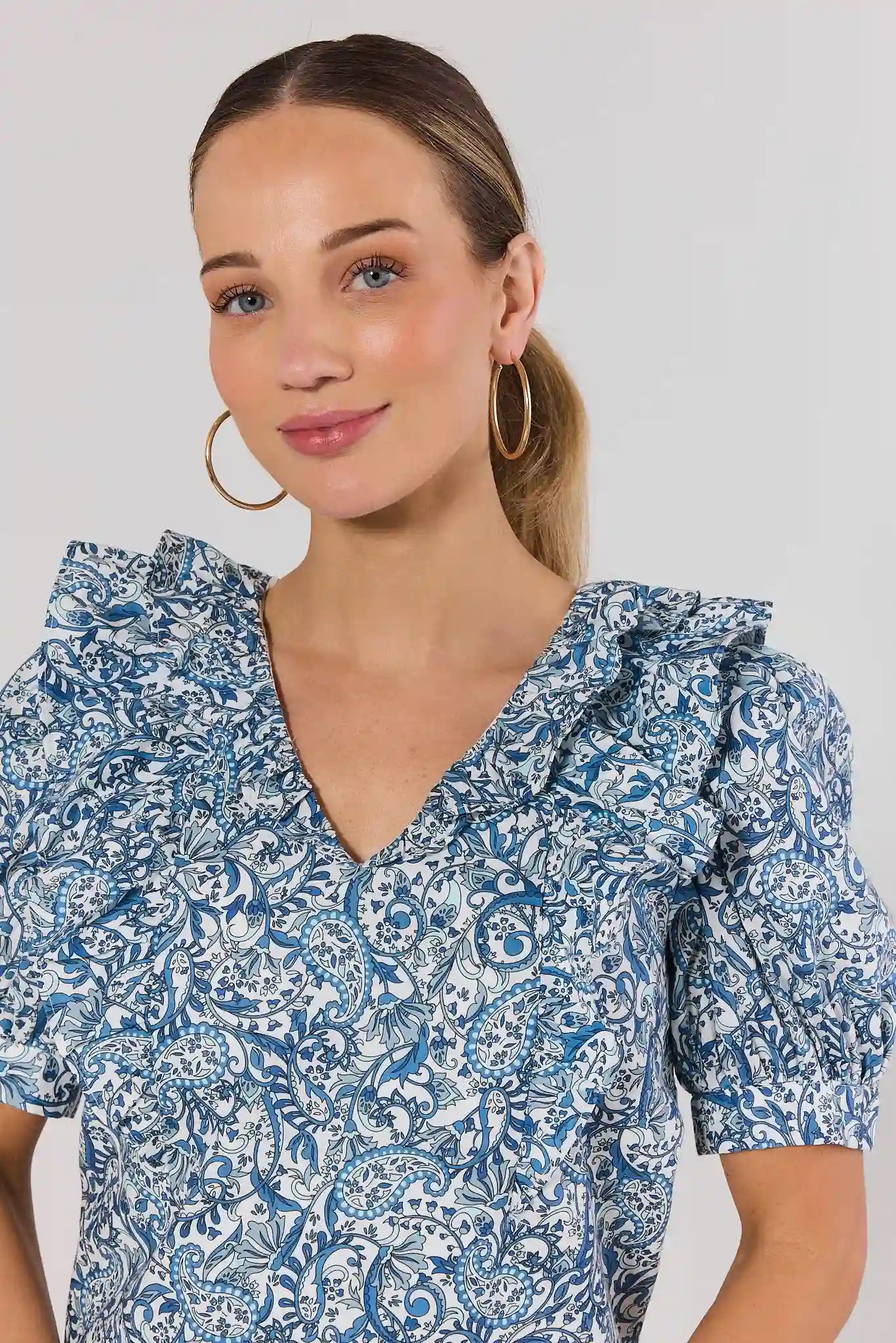 Woman wearing a blue floral dress against a plain background close up 
