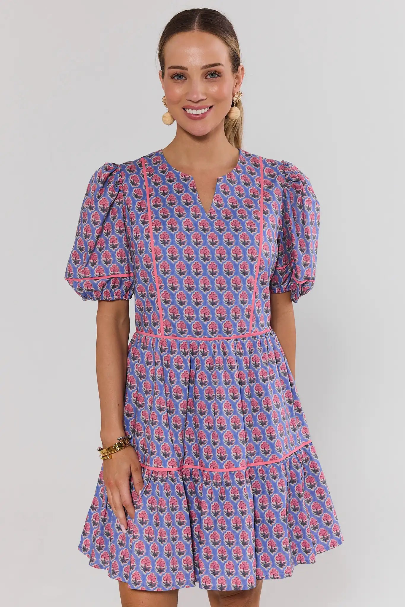 Woman wearing a landry blue and pink patterned dress on a plain background