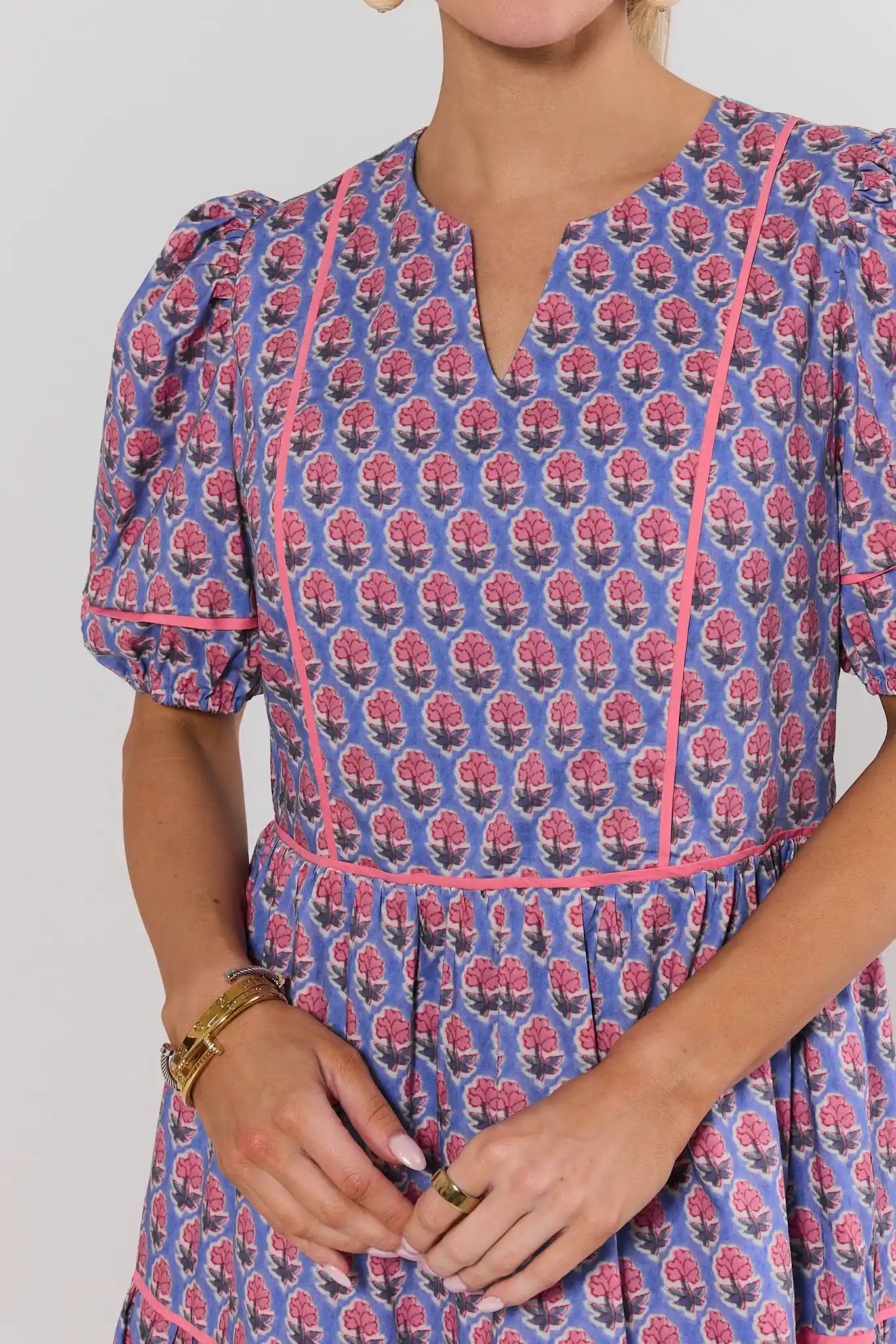 close up landry Woman wearing a blue dress with pink floral pattern on a plain background