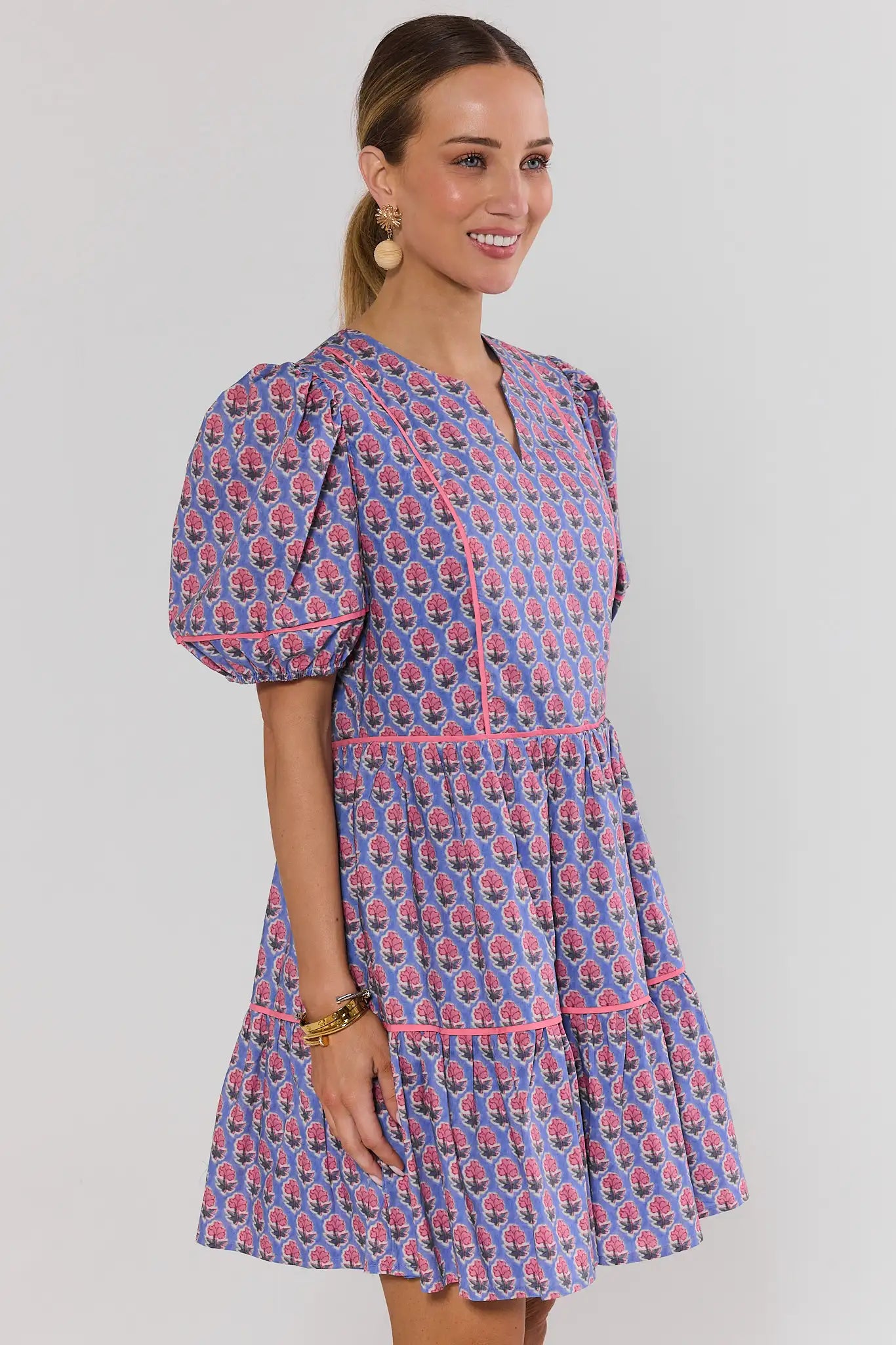 side shot Woman wearing a blue and pink patterned dress on a plain background