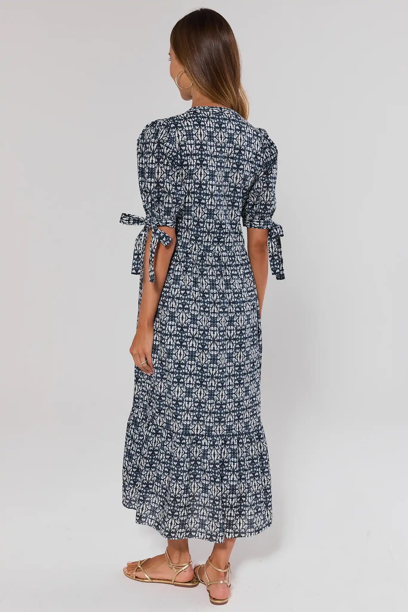 Woman standing wearing a black and white patterned dress on a white background