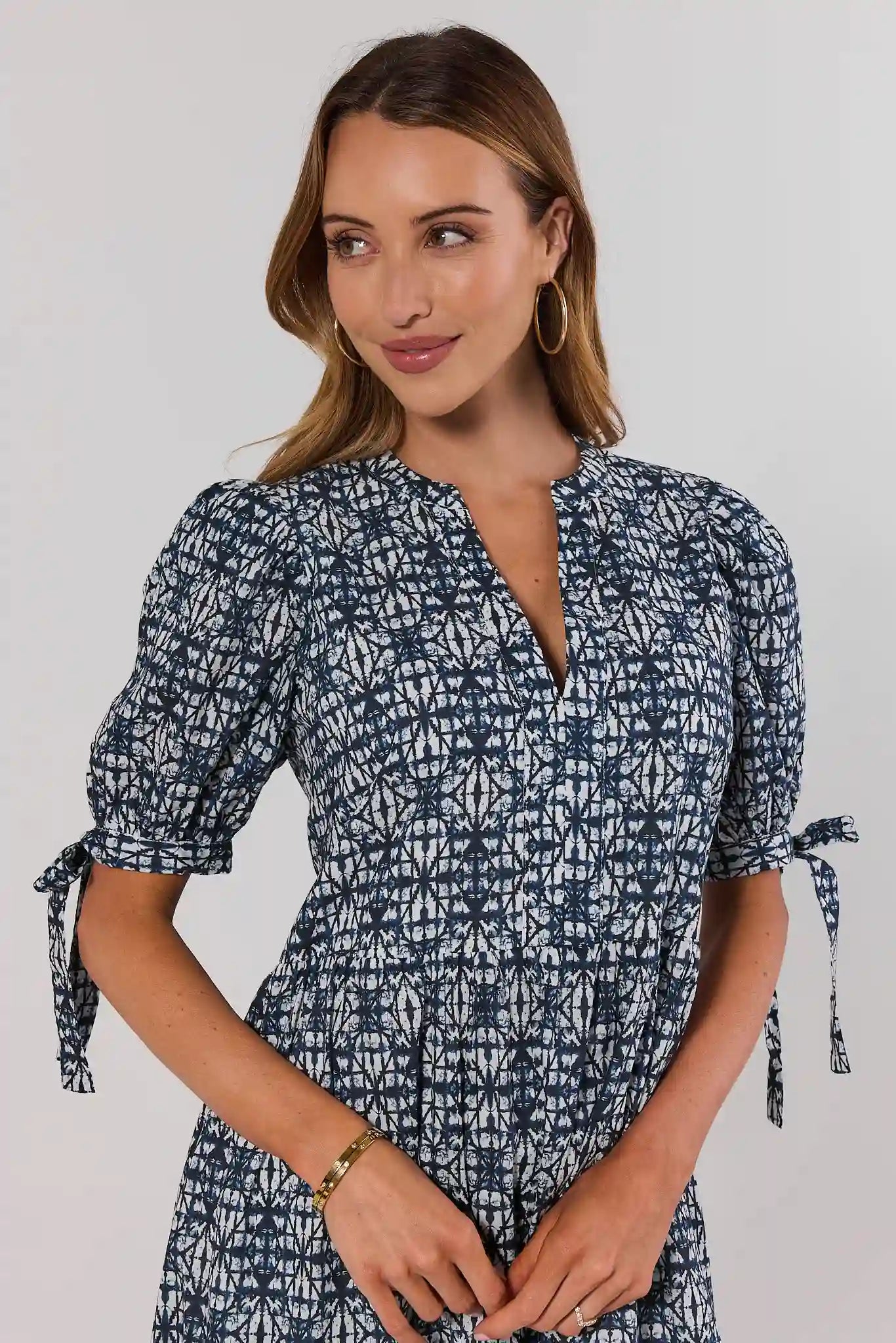 close up Woman wearing a blue patterned dress with puff sleeves on a plain background