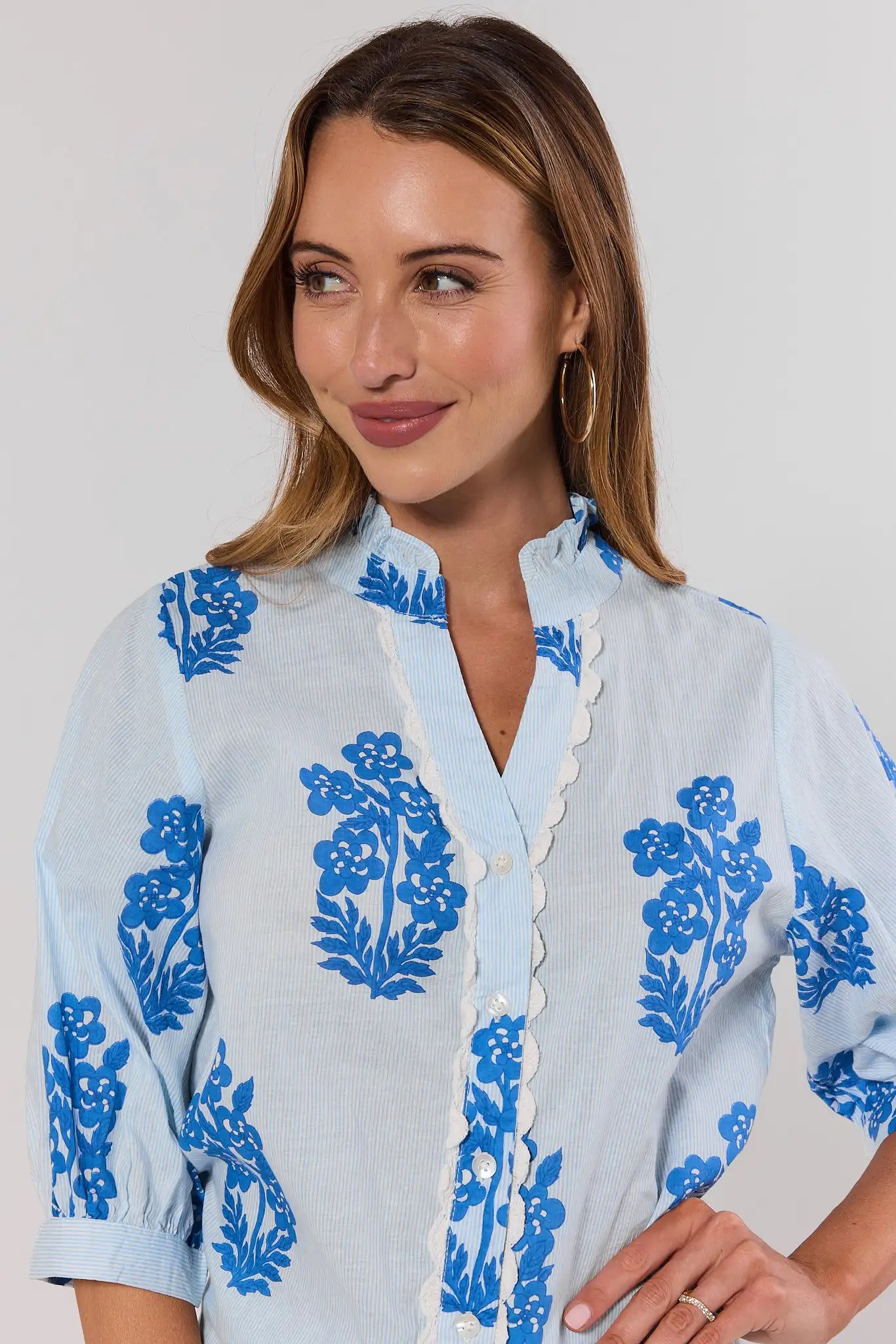close up Woman wearing a light blue blouse with blue floral patterns on a plain background